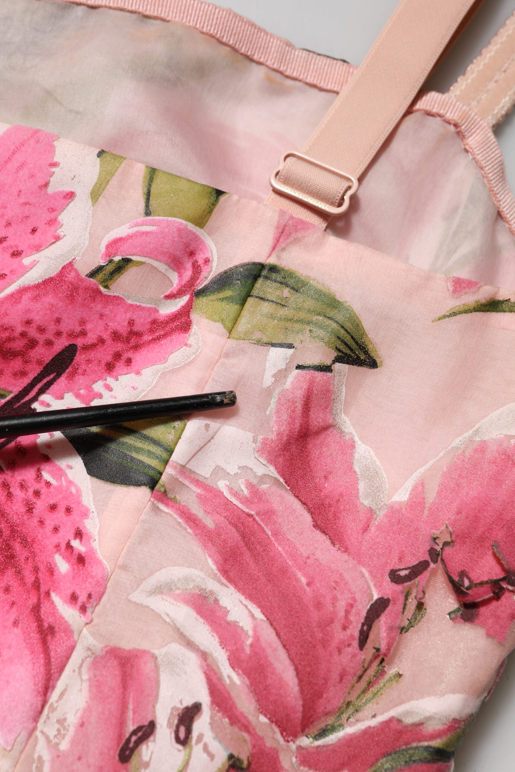 A pink floral midi dress with lily print, sleeveless and featuring a tie at the waist