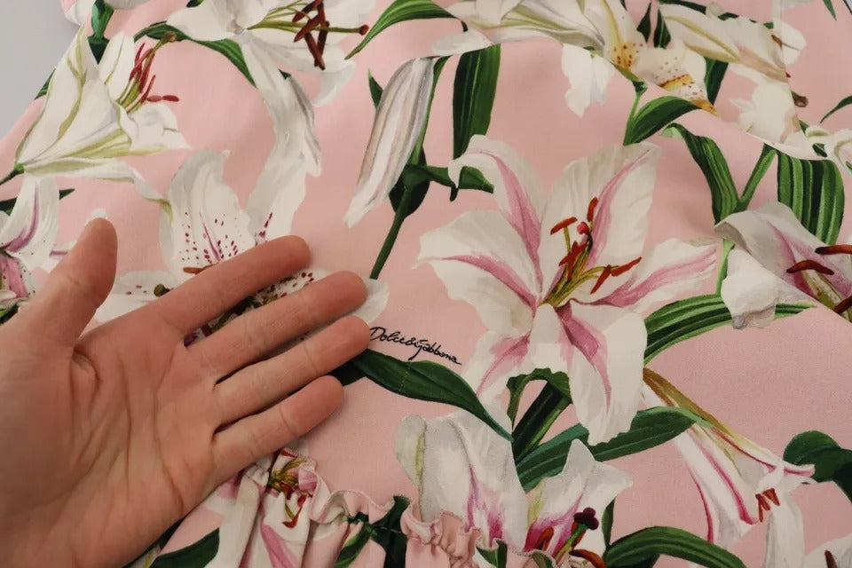 A person's hand on a pink lily print dress with a sheer viscose fabric