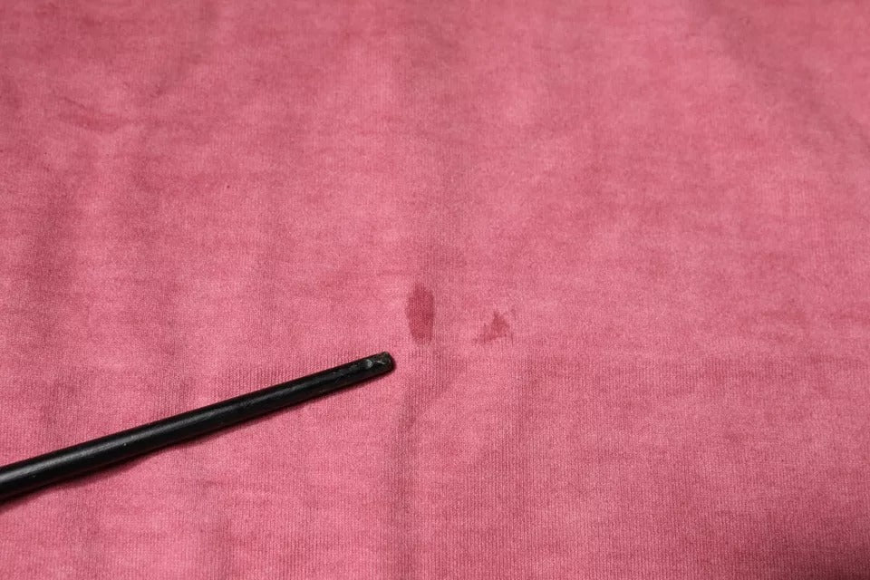 Black metal object on pink cloth