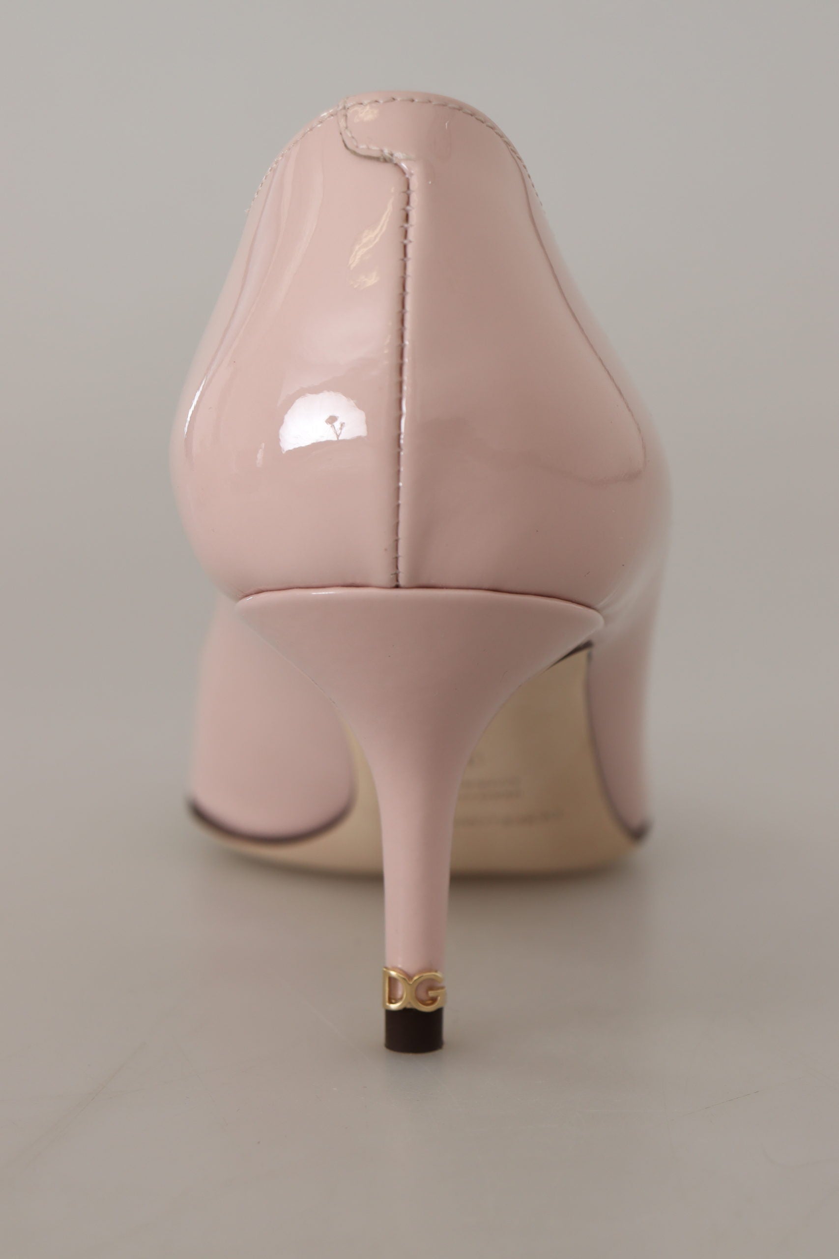 Pink high heel shoe with pointed toe and gold accent on sole