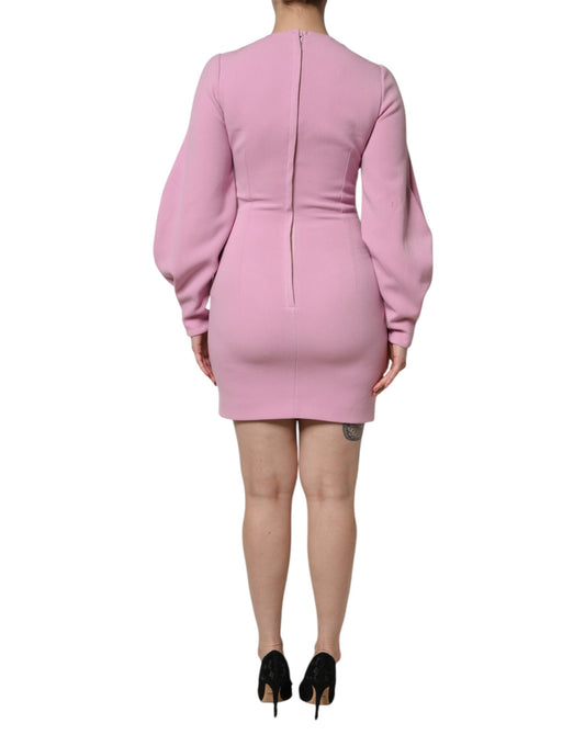 A pink sheath dress with long sleeves and a high neckline
