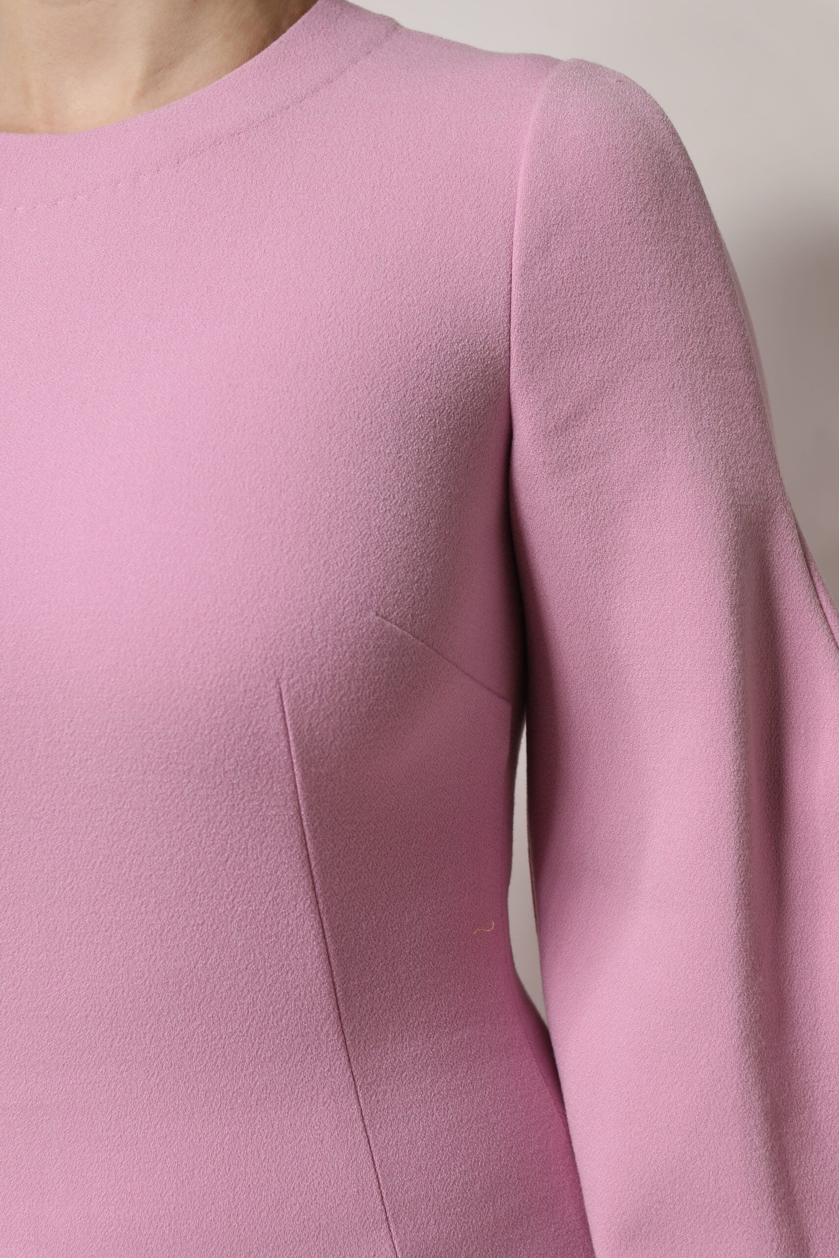 A pink polyester long sleeve sheath mini dress with a ruffled shoulder