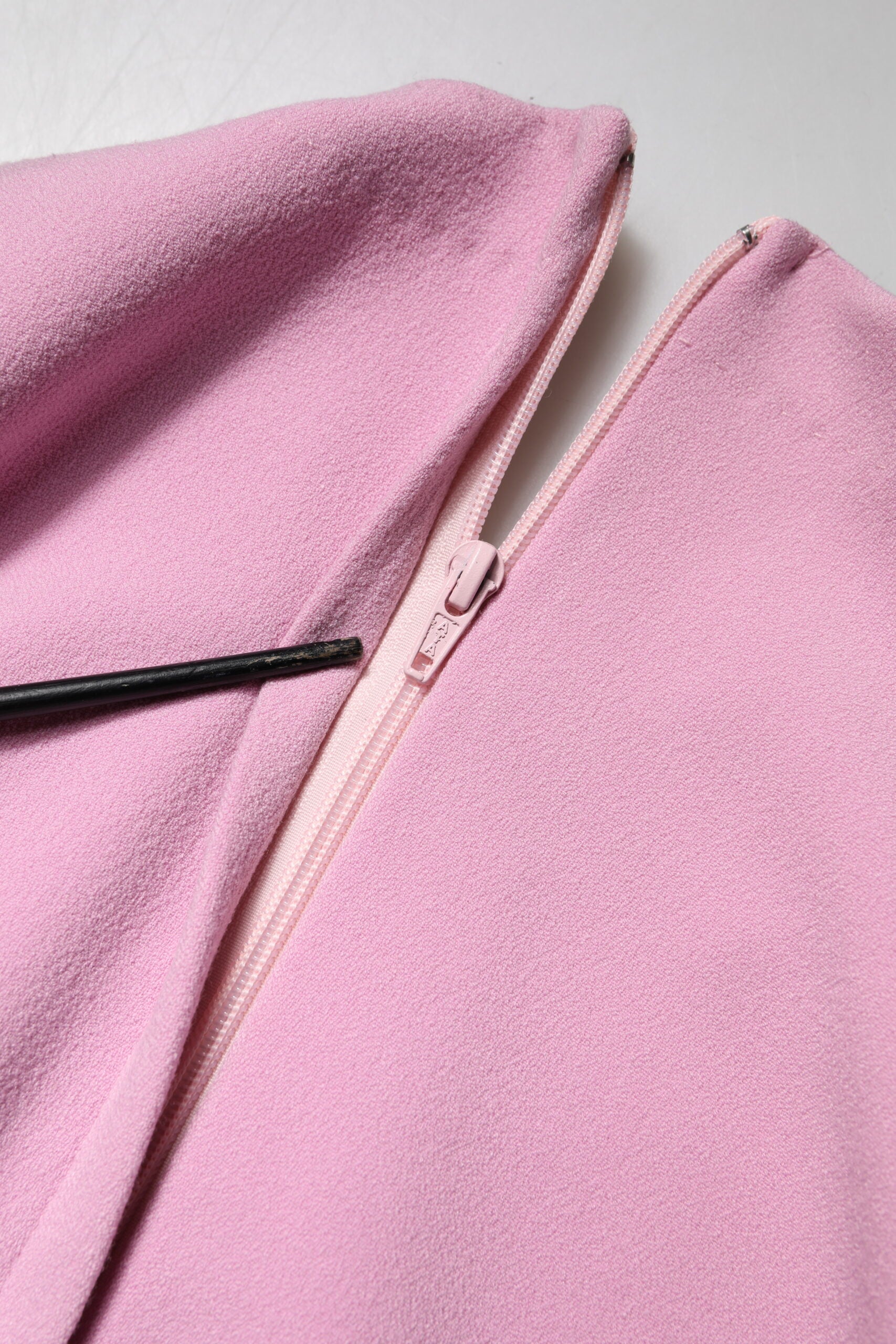 A pink polyester dress with long sleeves and a sheath style