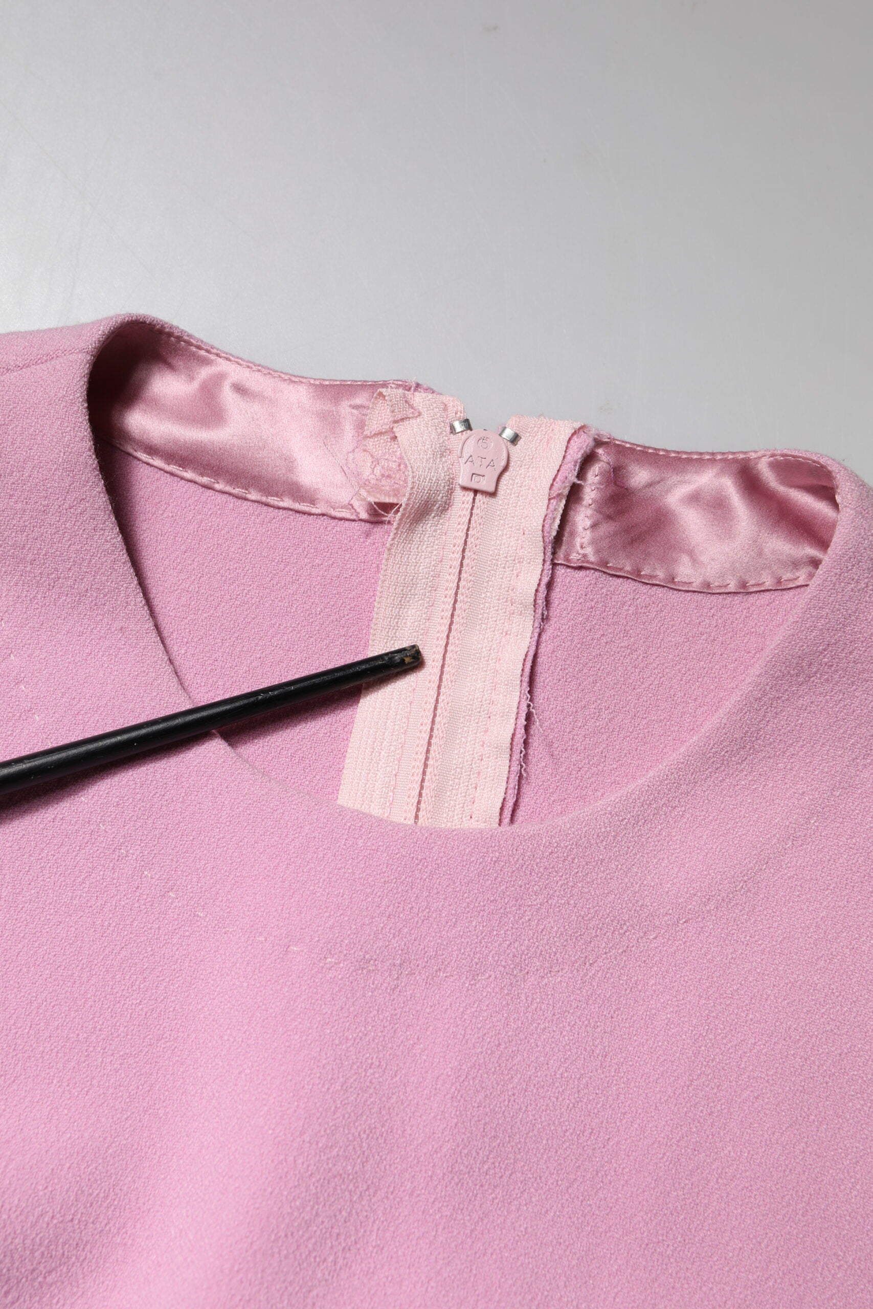 A pink polyester dress with long sleeves and a sheath style