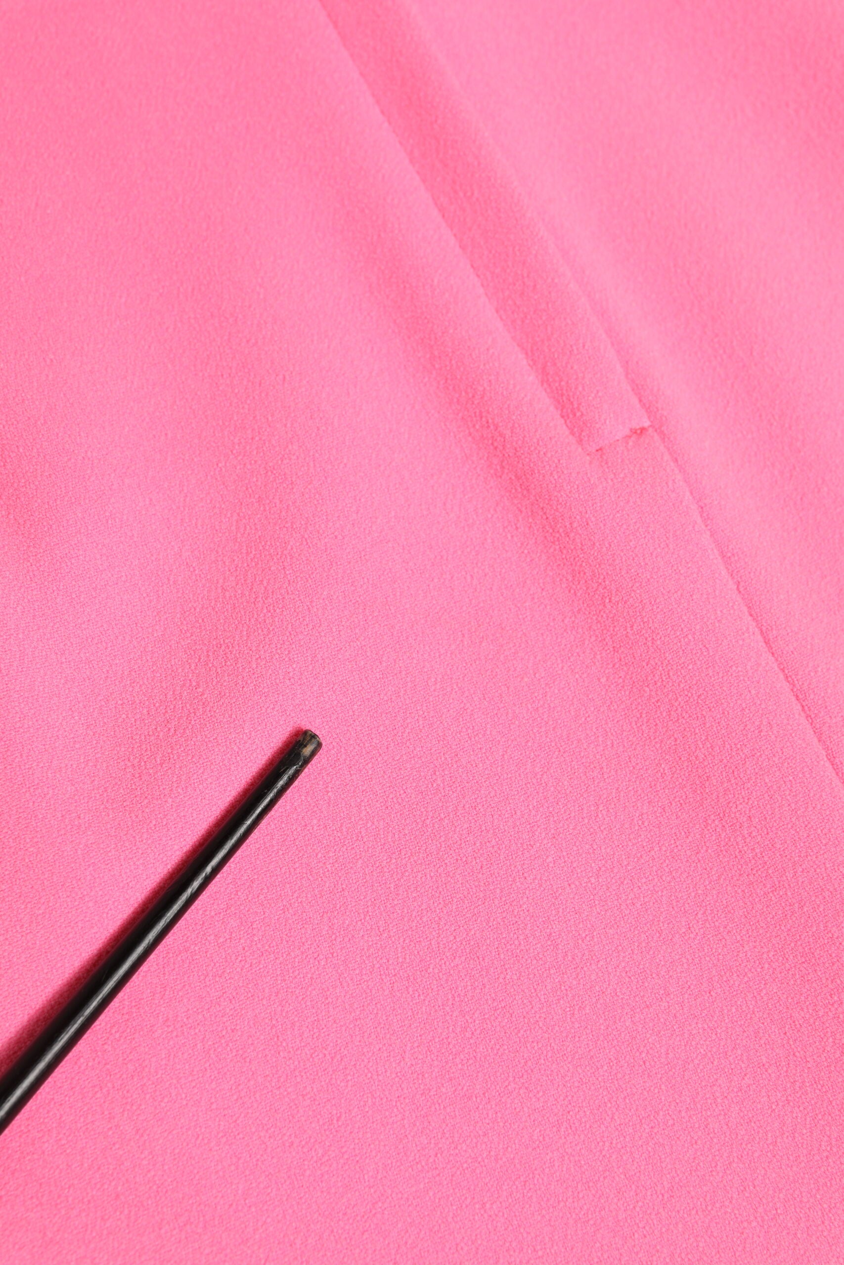 A black pen on a pink fabric surface