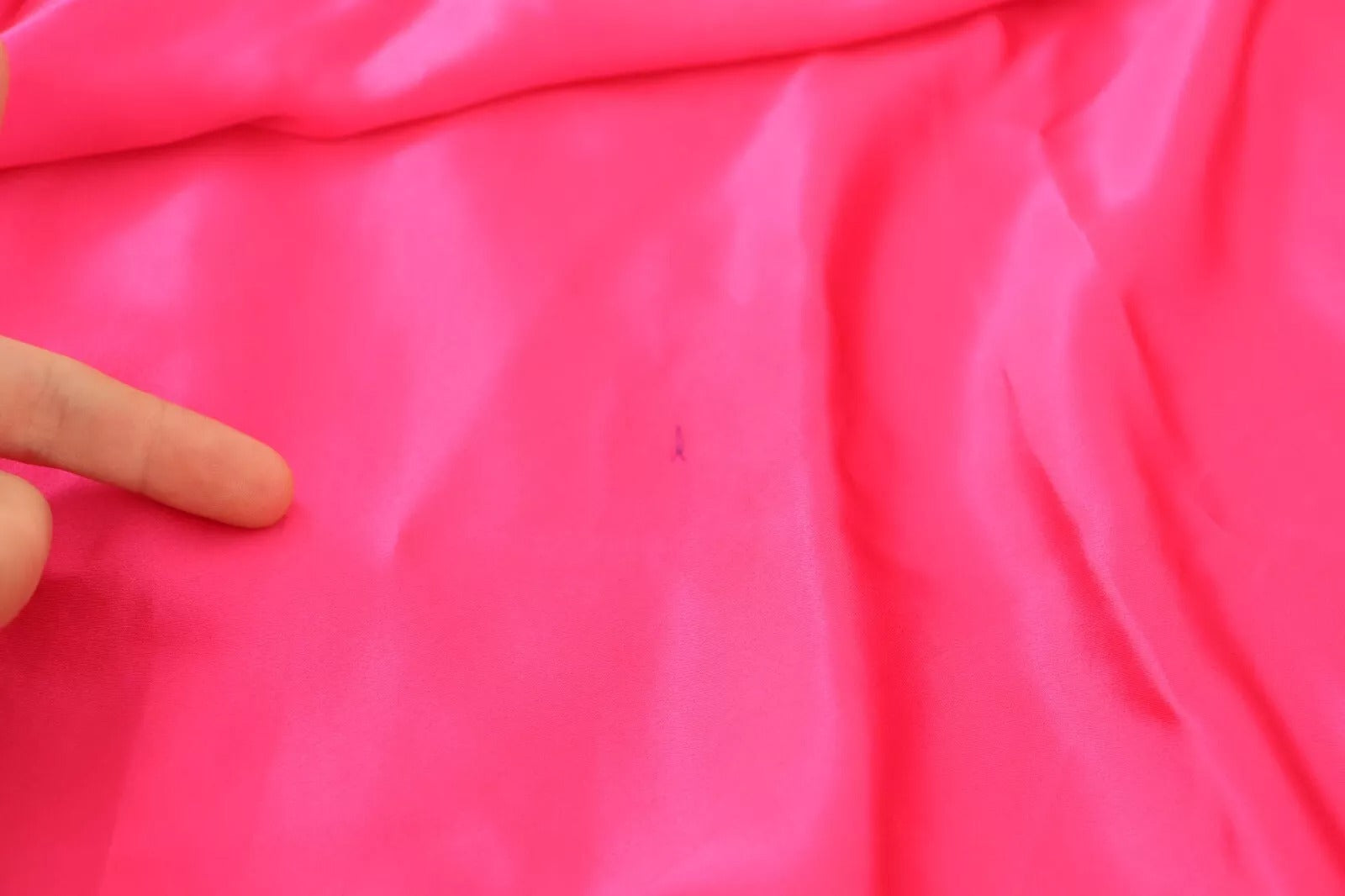 Pink fabric with finger pointing at it