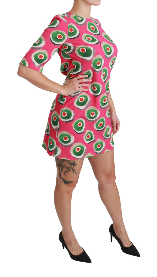 A woman wearing a pink dress with cupcake print and black heels