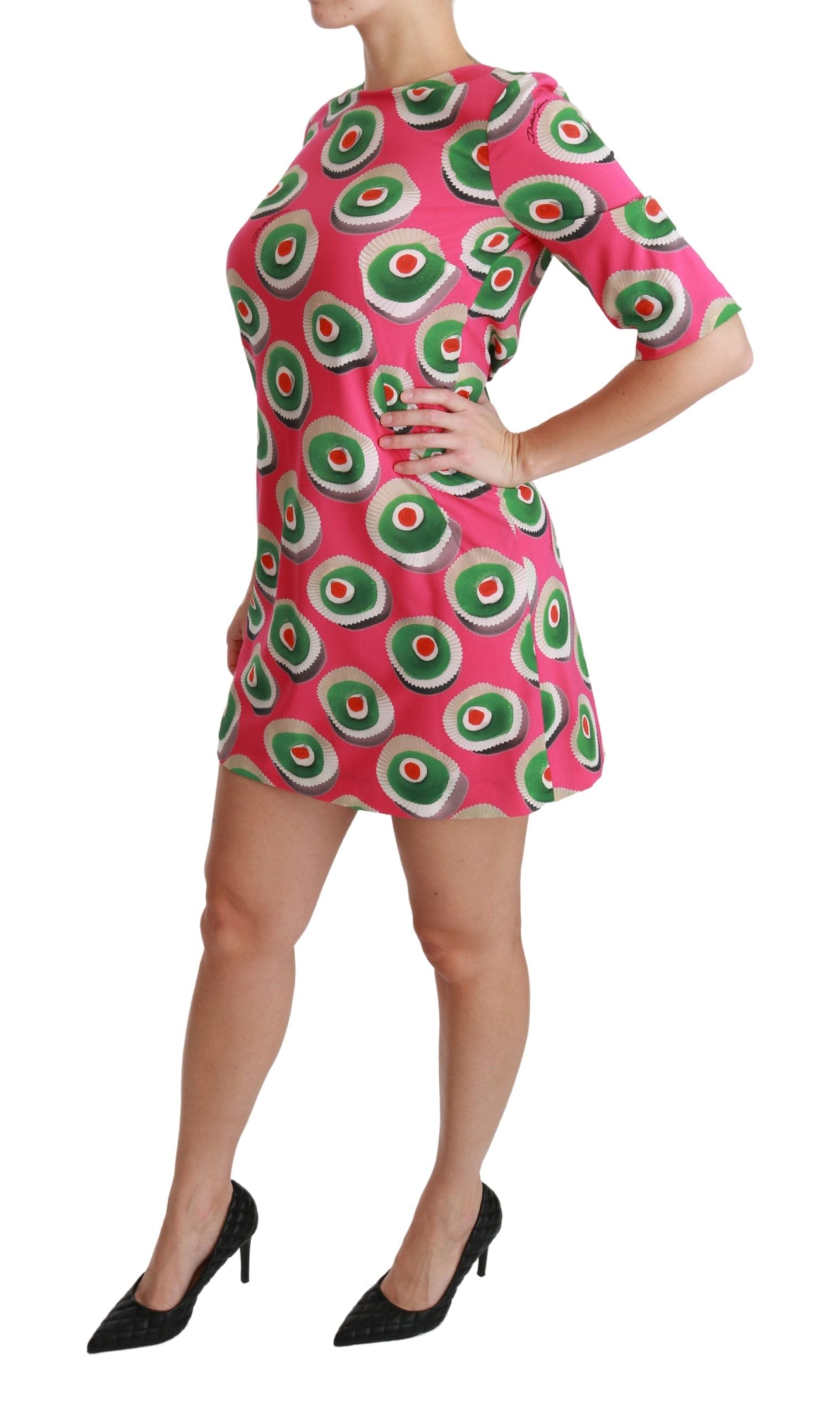 A woman wearing a pink dress with green and red circles