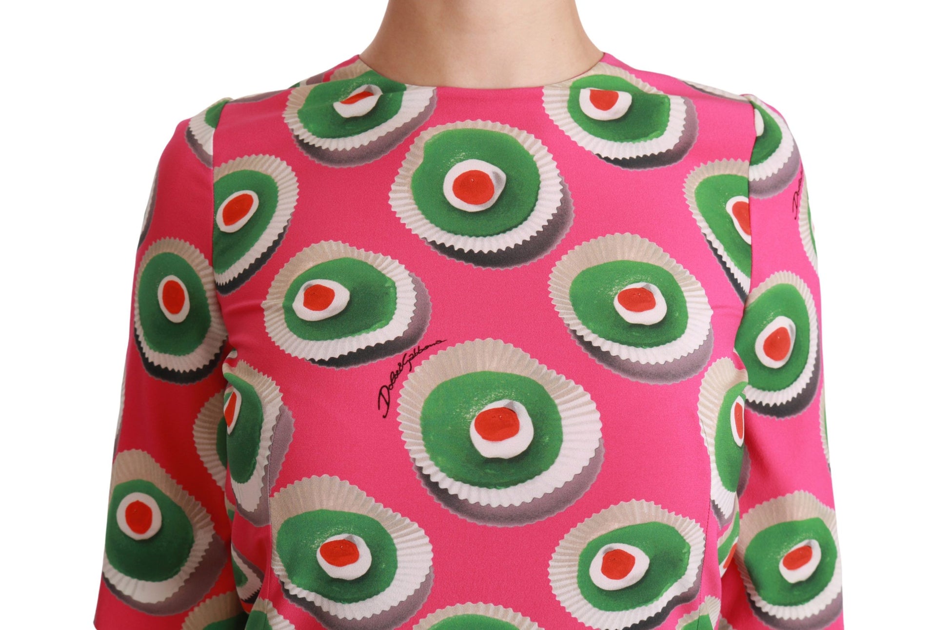 A pink silk dress with a cupcake pattern and green and red accents
