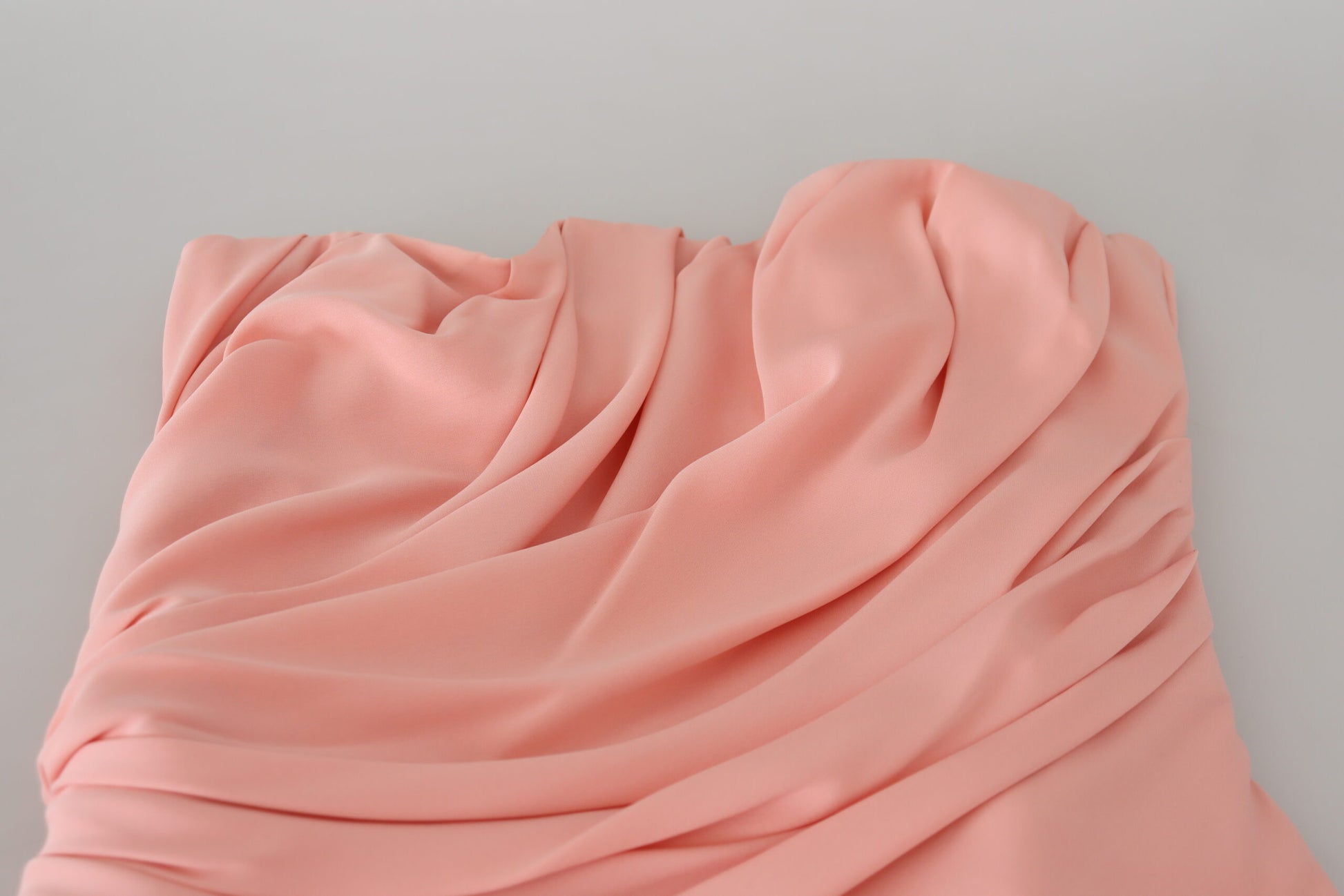 A pink silk stretch strapless sheath dress with ruffled detailing