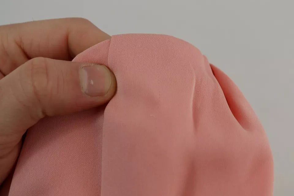 A person's hand holding a pink silk stretch strapless sheath midi dress