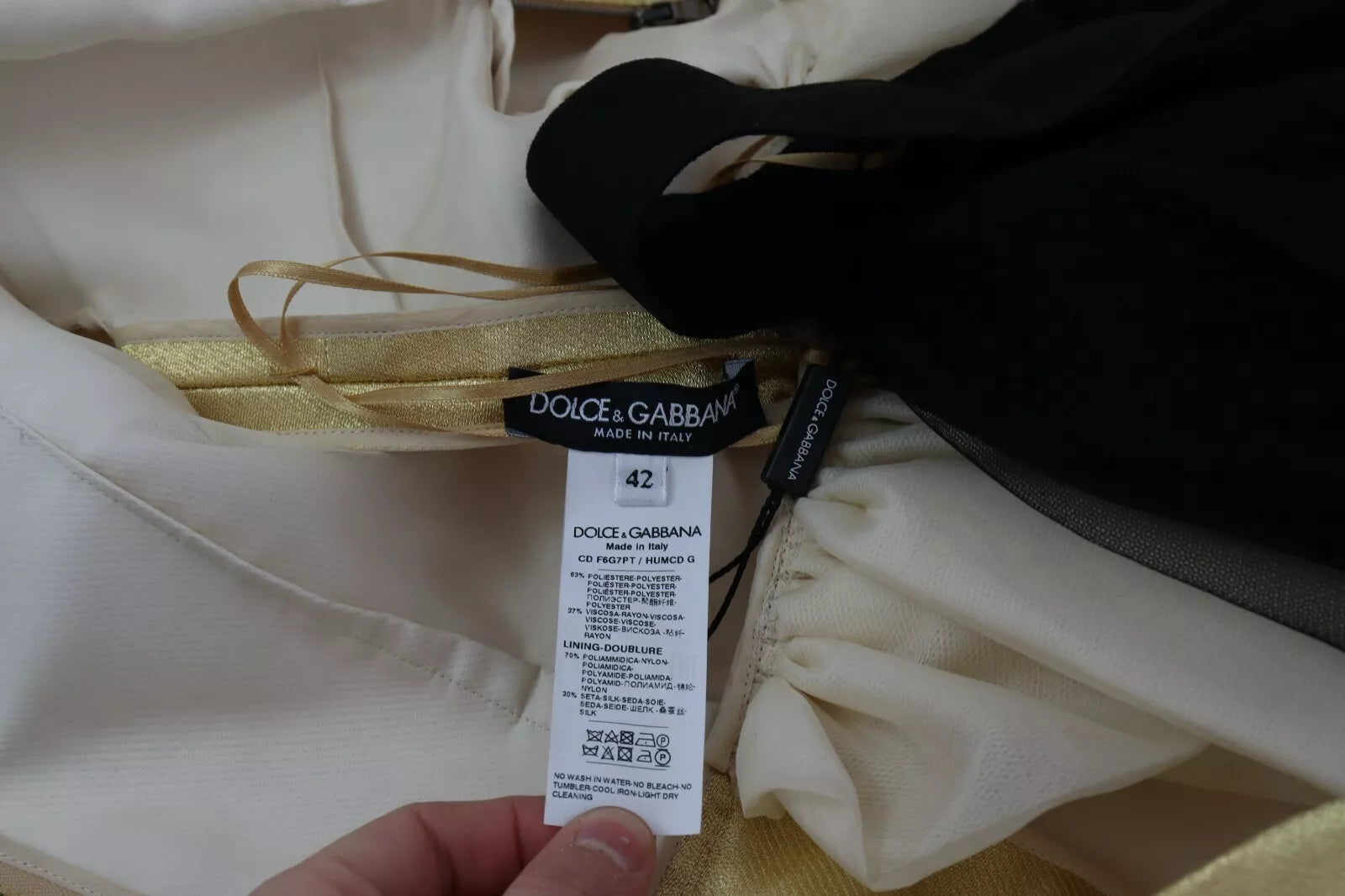 A close-up of a dress with gold tulle fabric and a label that reads "Dolce & Gabbana