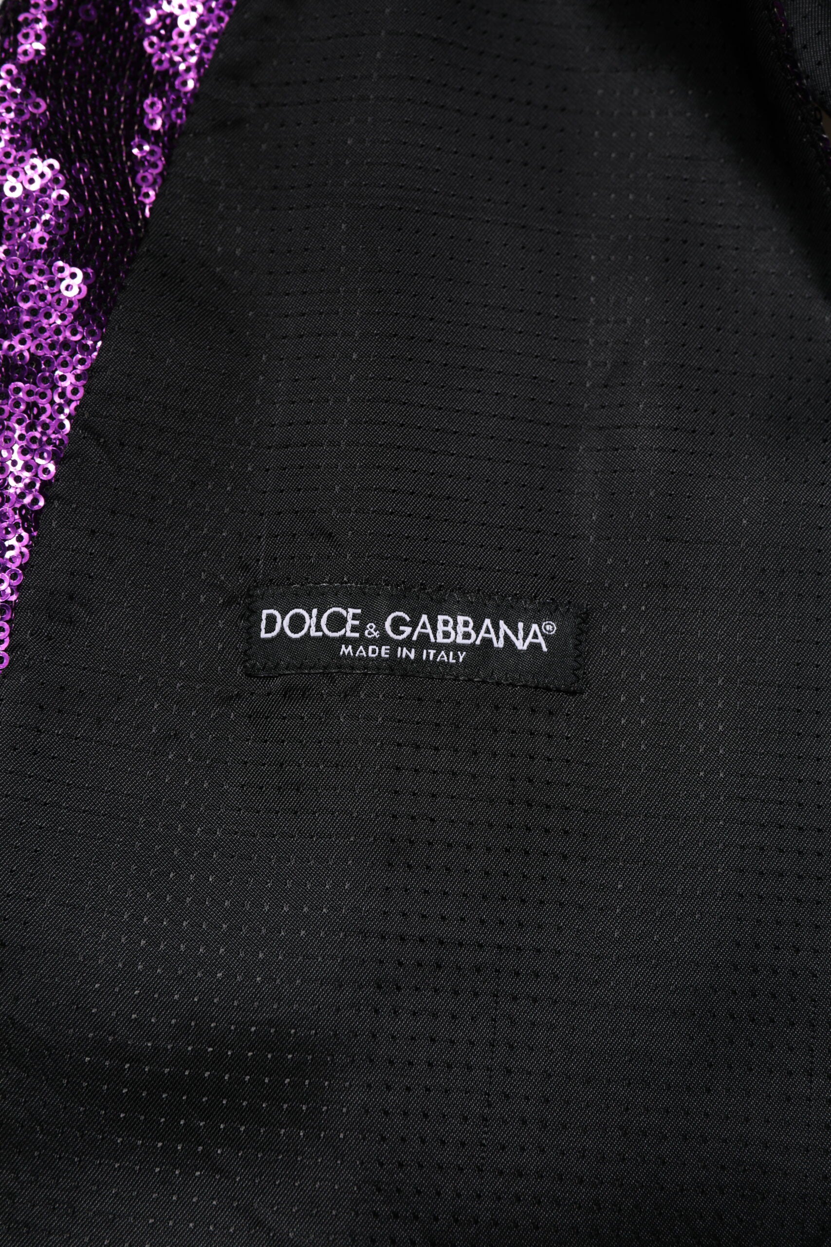 A black vest with a purple sequin pattern and the Dolce & Gabbana logo