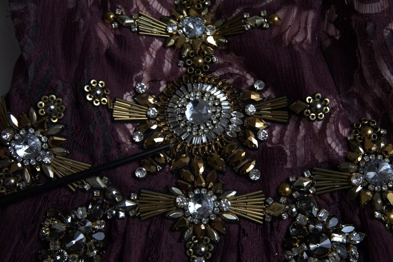 A close-up of a purple viscose dress with crystal embellishments. It features an A-line silhouette and is des