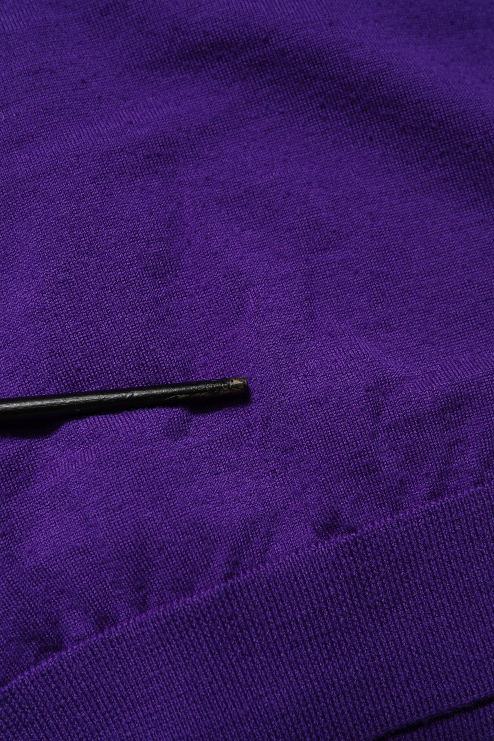 Black sewing needle on purple fabric