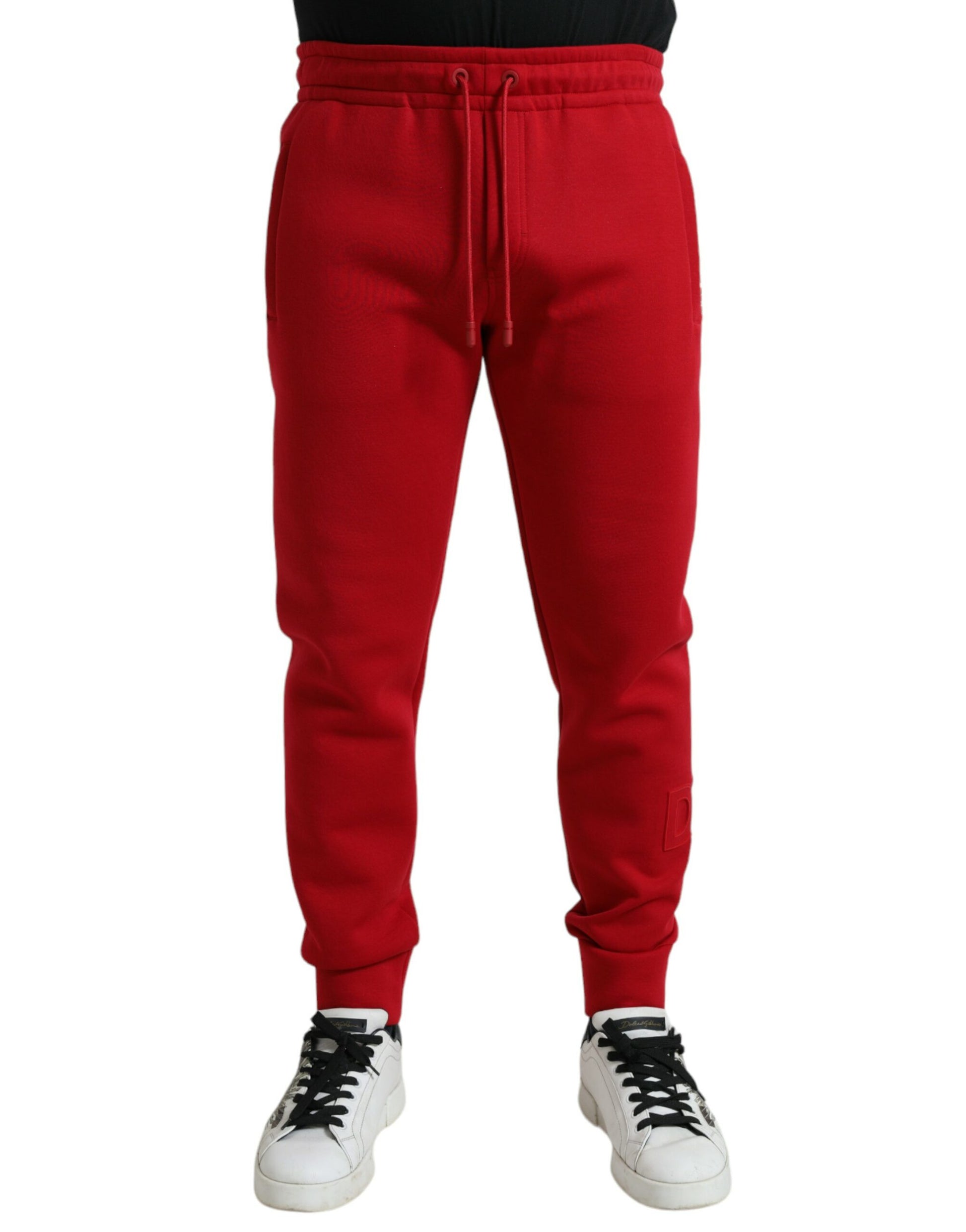 Red sweatpants on a person wearing black sneakers
