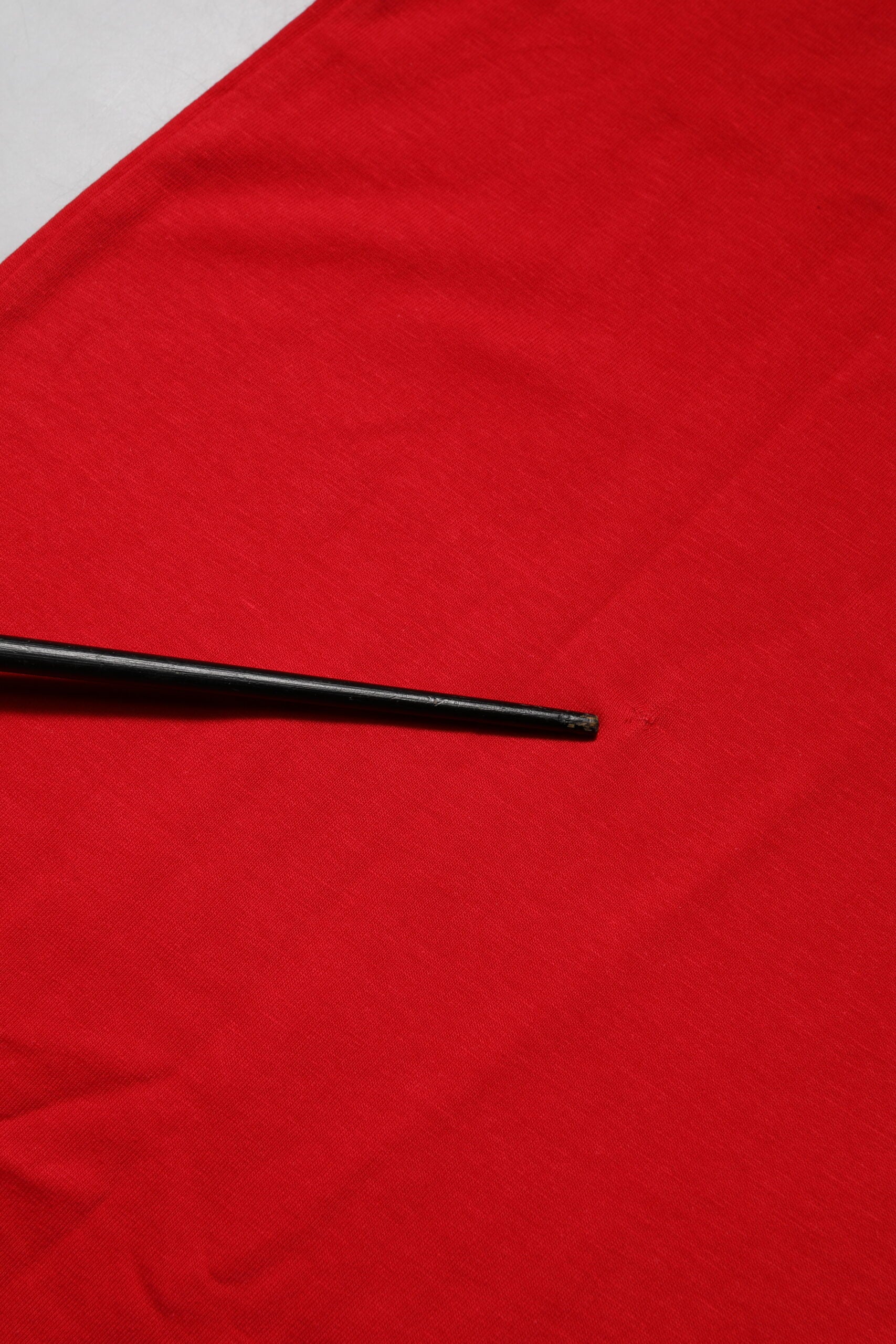 Black sewing needle on red fabric