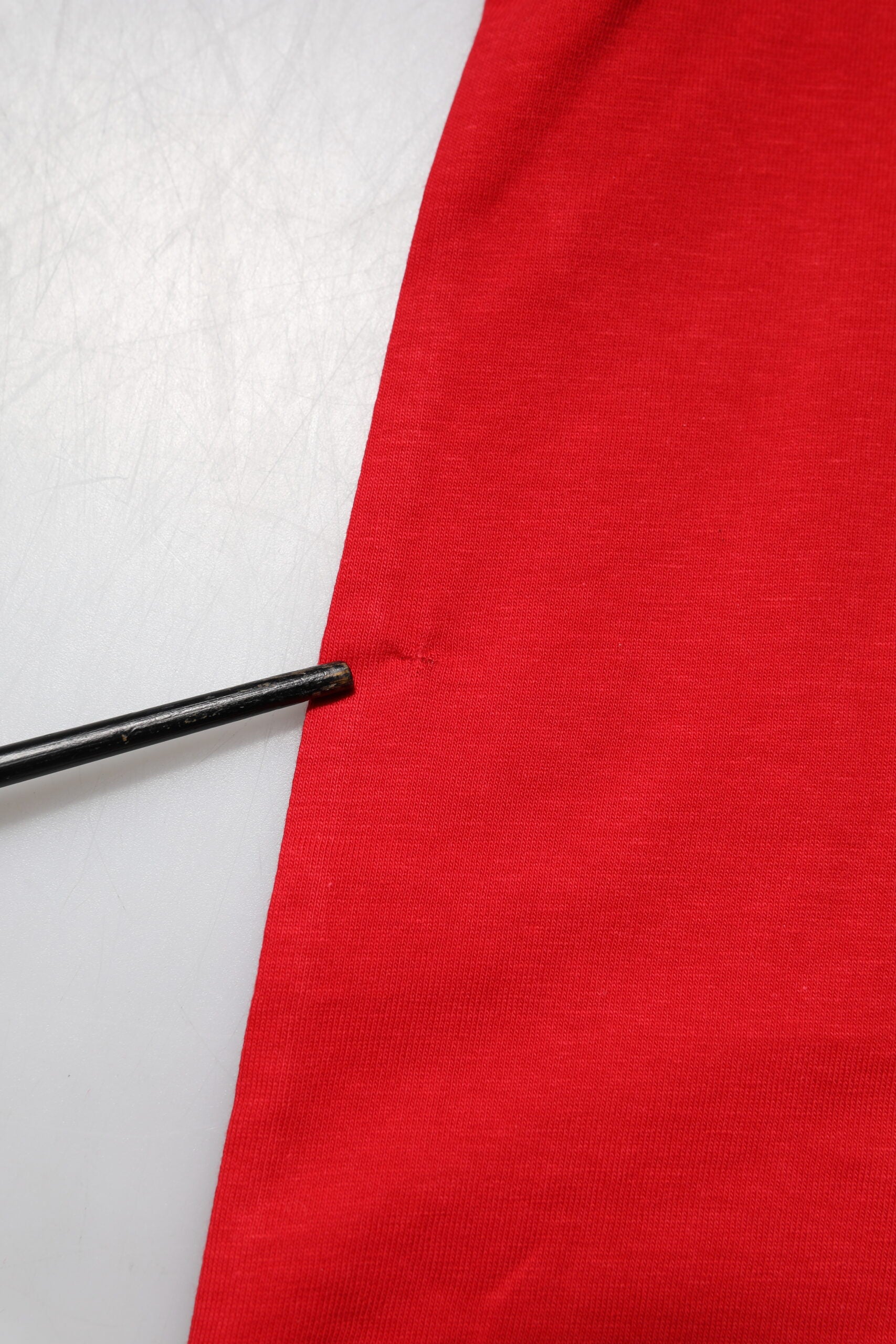 Red and white jersey with a black pin in it