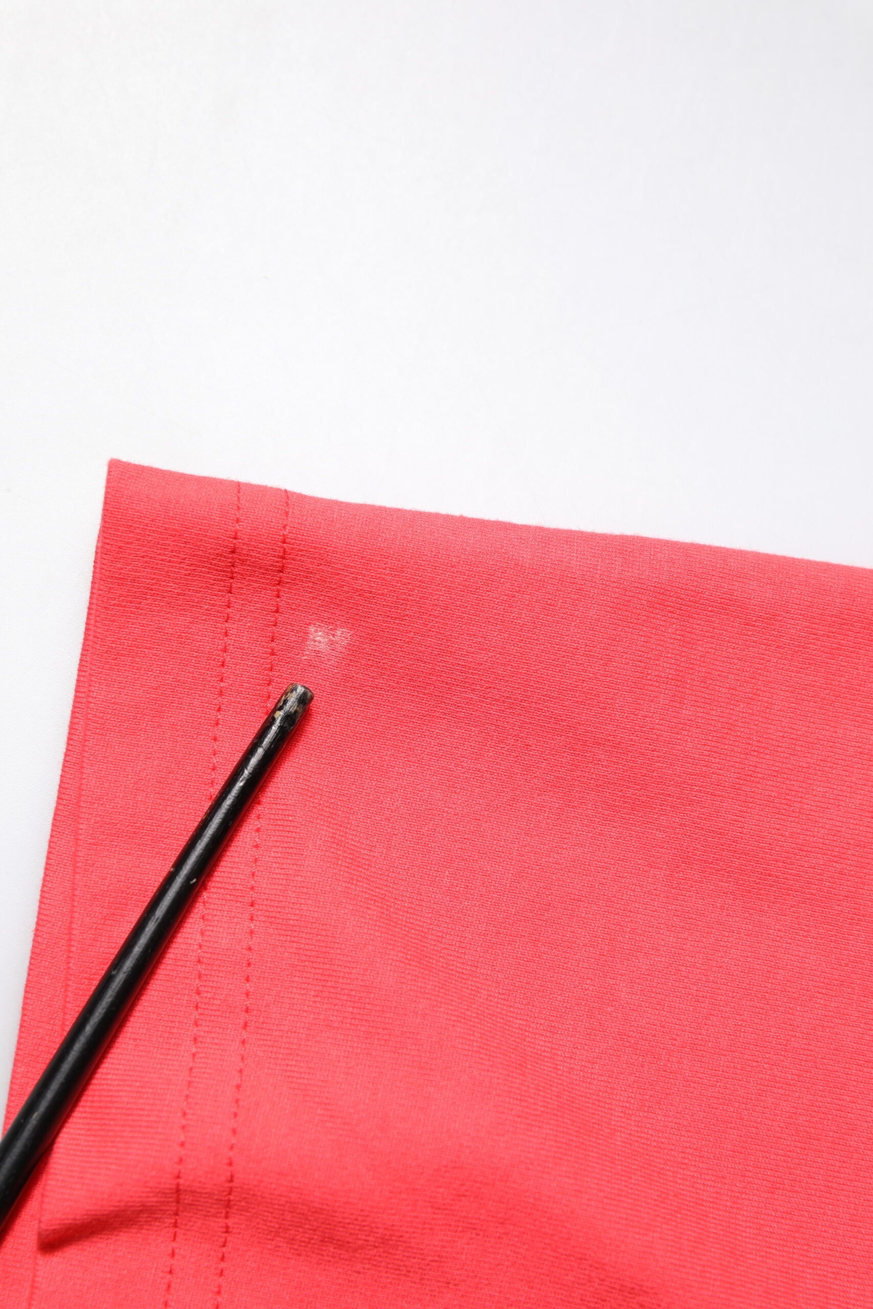 Black sewing needle on red fabric