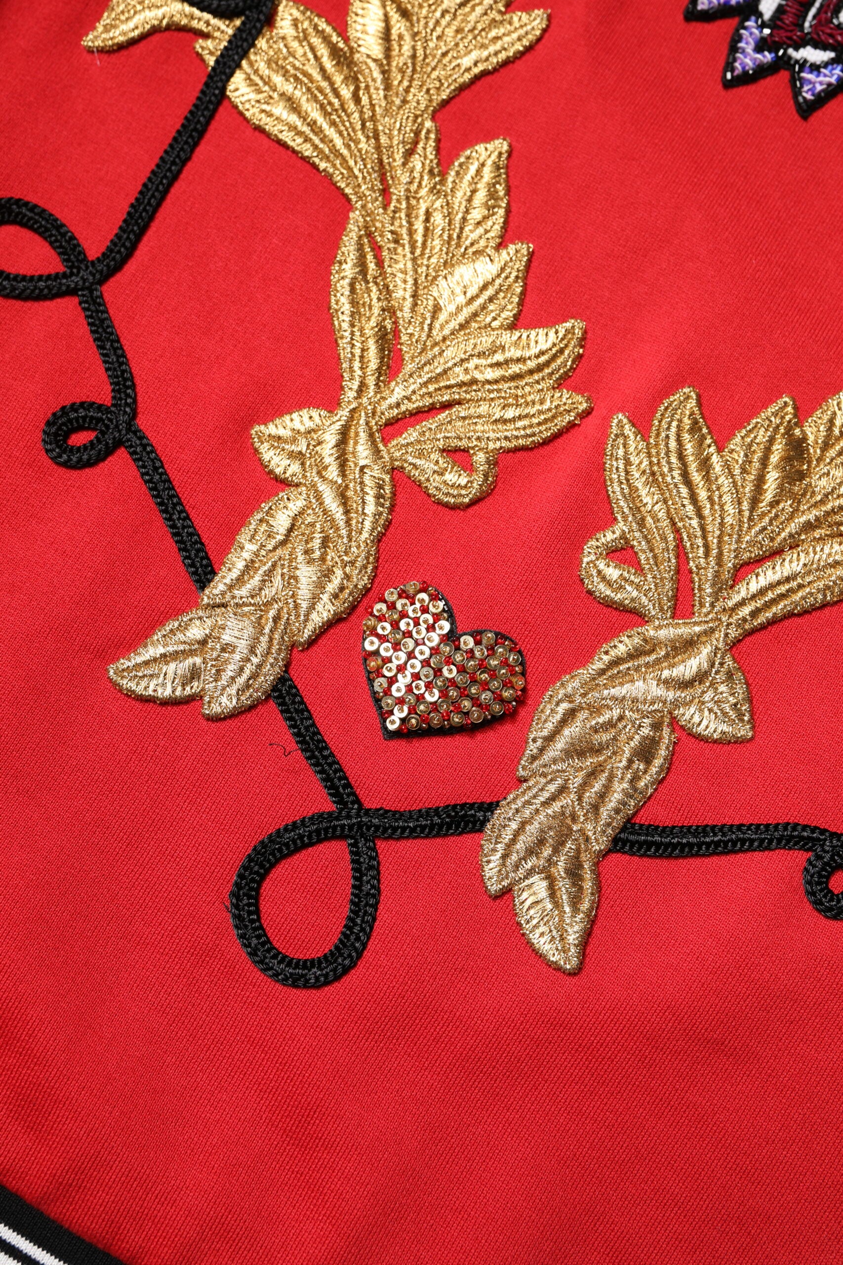 Red embroidered garment with gold leaf design and heart charm