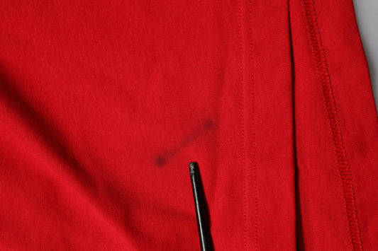 Red fabric with black stitching and a small hole