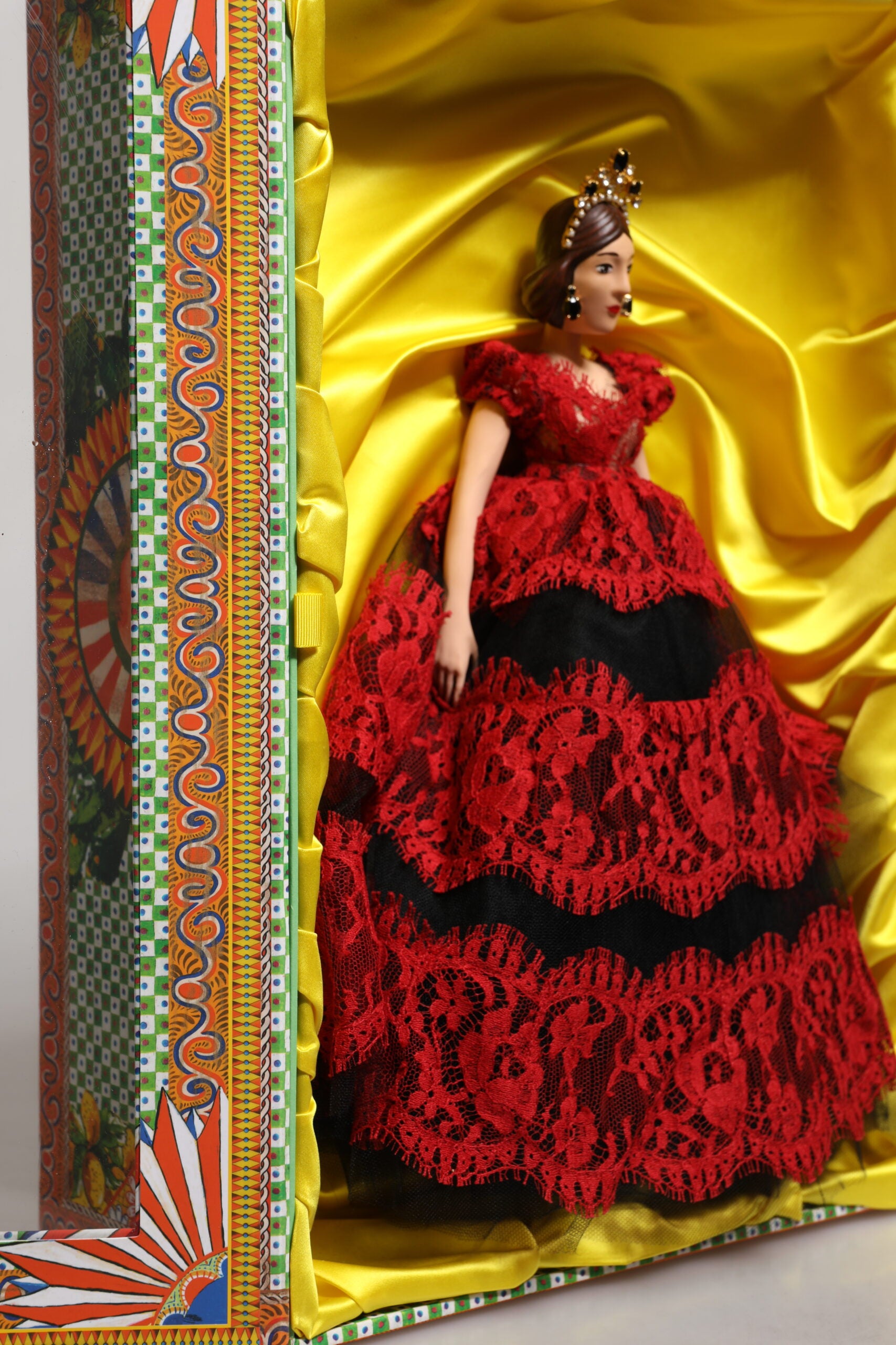 A porcelain doll wearing a red dress with lace detailing