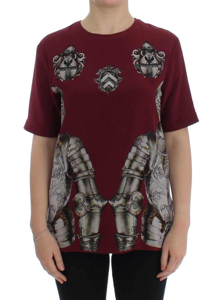 Woman wearing a maroon shirt with a design of armor on the front
