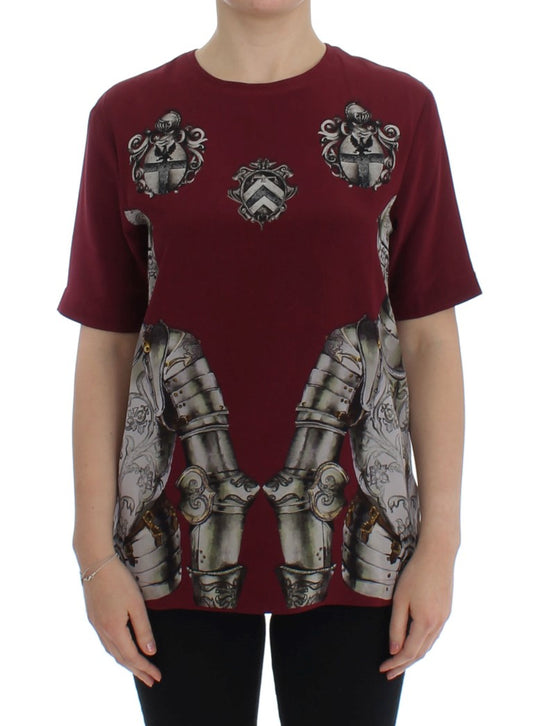 Woman wearing a maroon shirt with a design of armor on the front