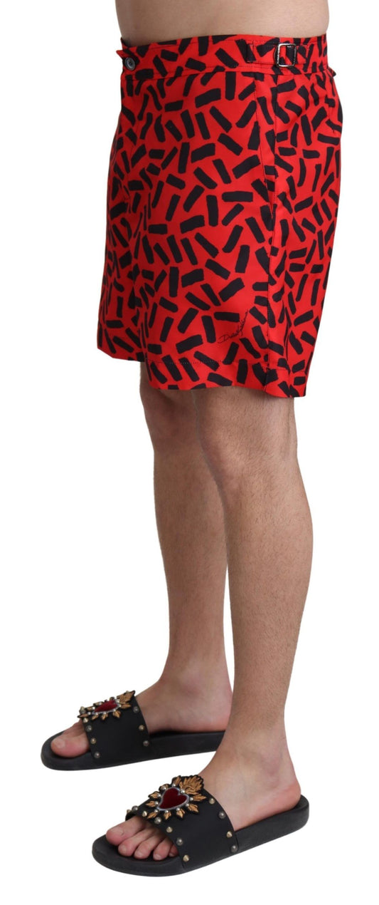 Man wearing red swim trunks with black pattern and sandals