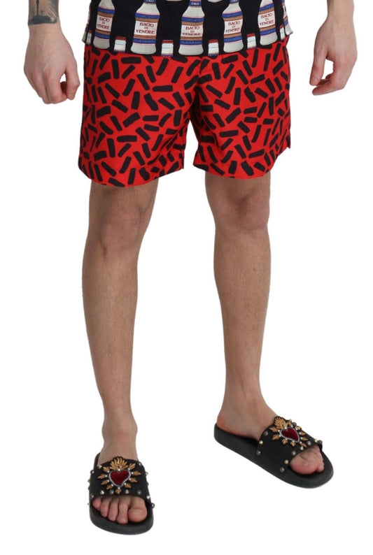 Man wearing red shorts with white bottles on them and black sandals