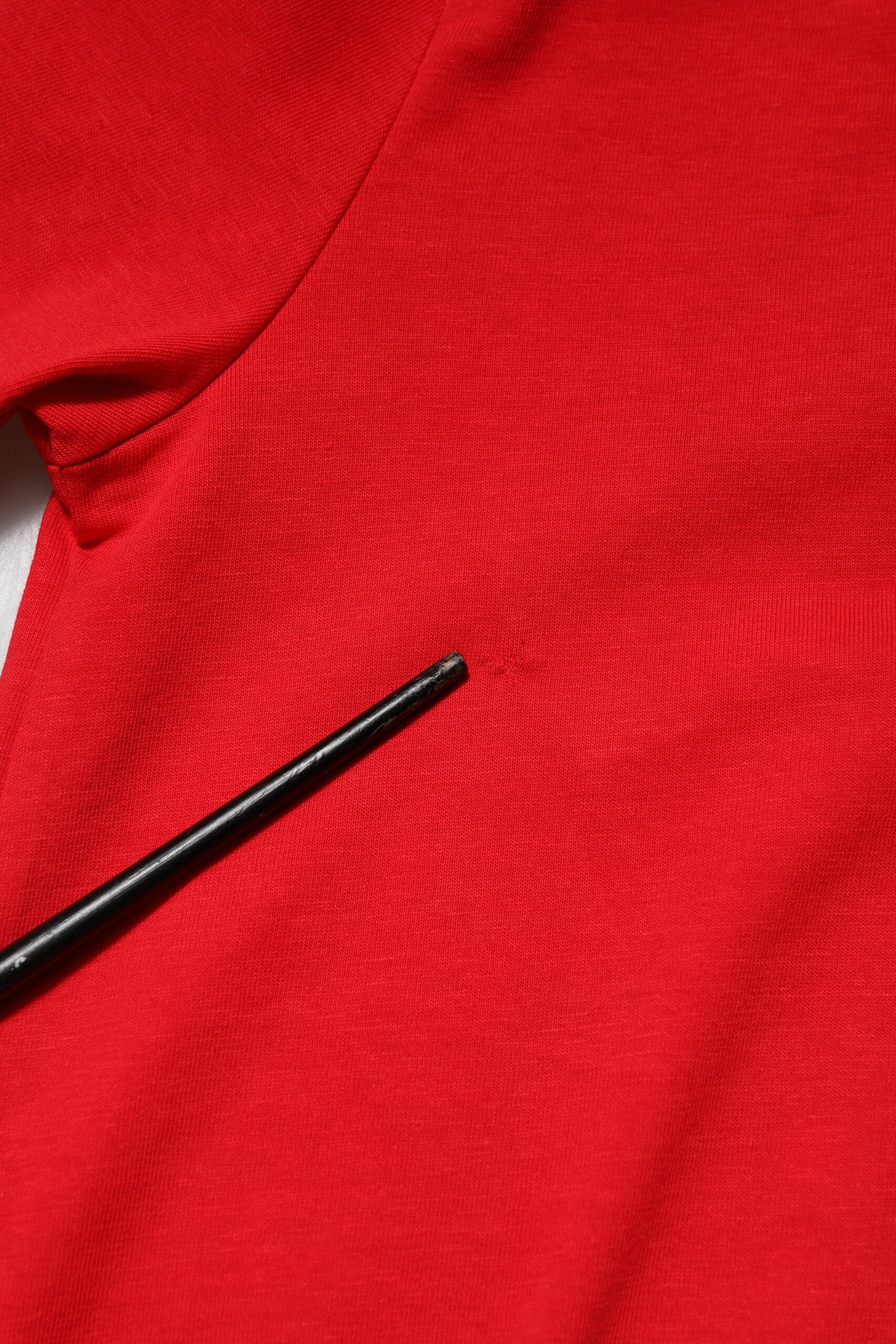 Red shirt with black pin in fabric