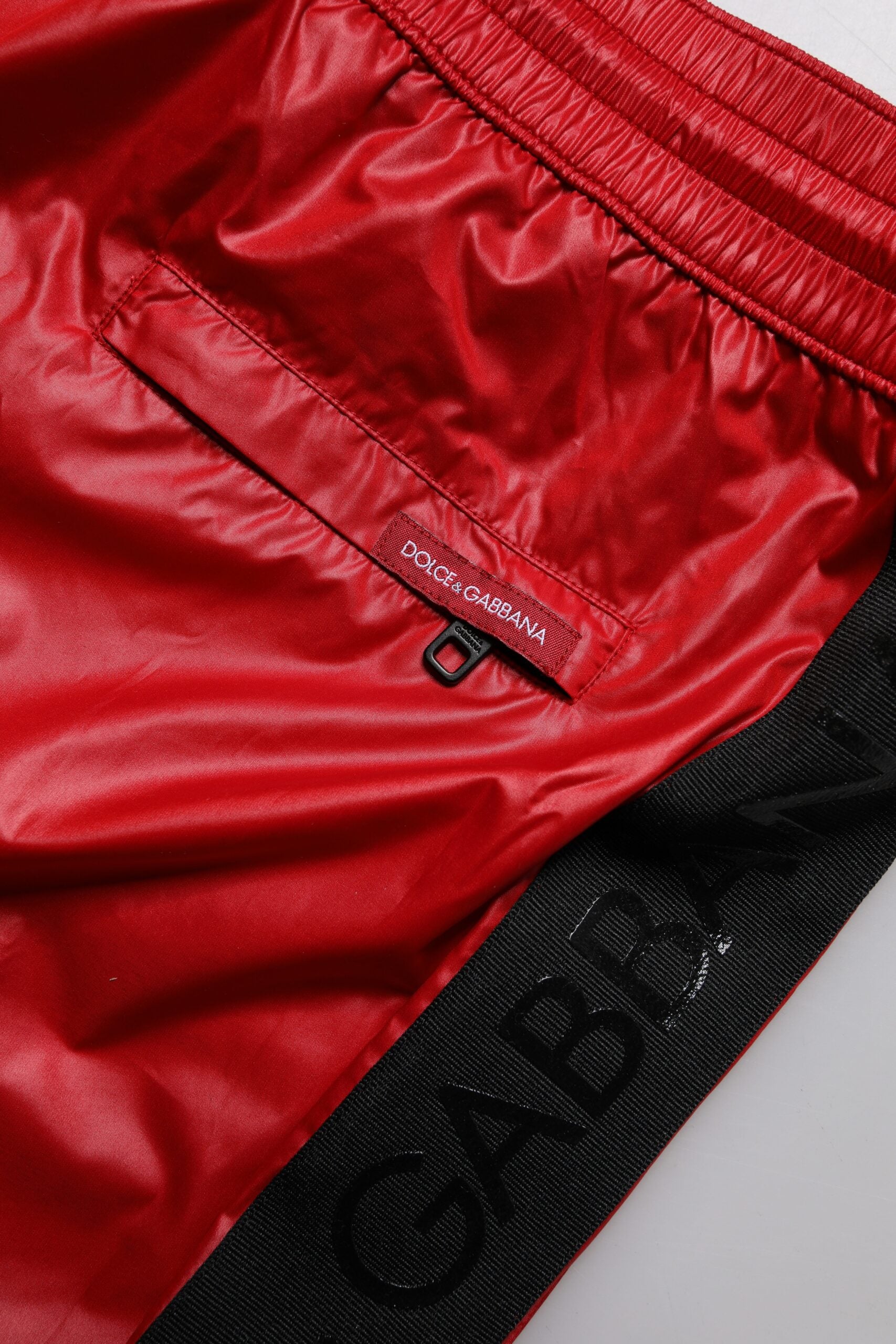 Red polyester beachwear shorts with black logo on waistband