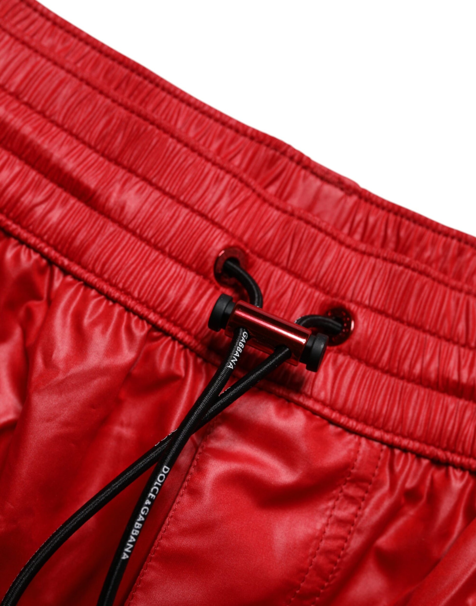 Red polyester beachwear shorts with black drawstring and brand logo