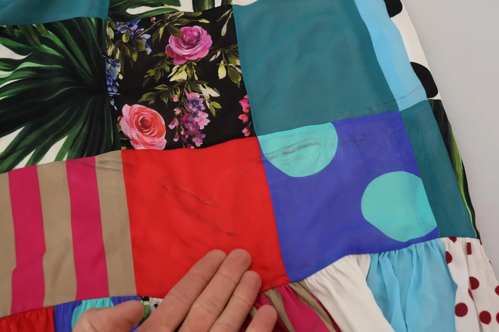 A colorful patchwork dress with floral and paisley patterns, in shades of blue, green, red, yellow, and white