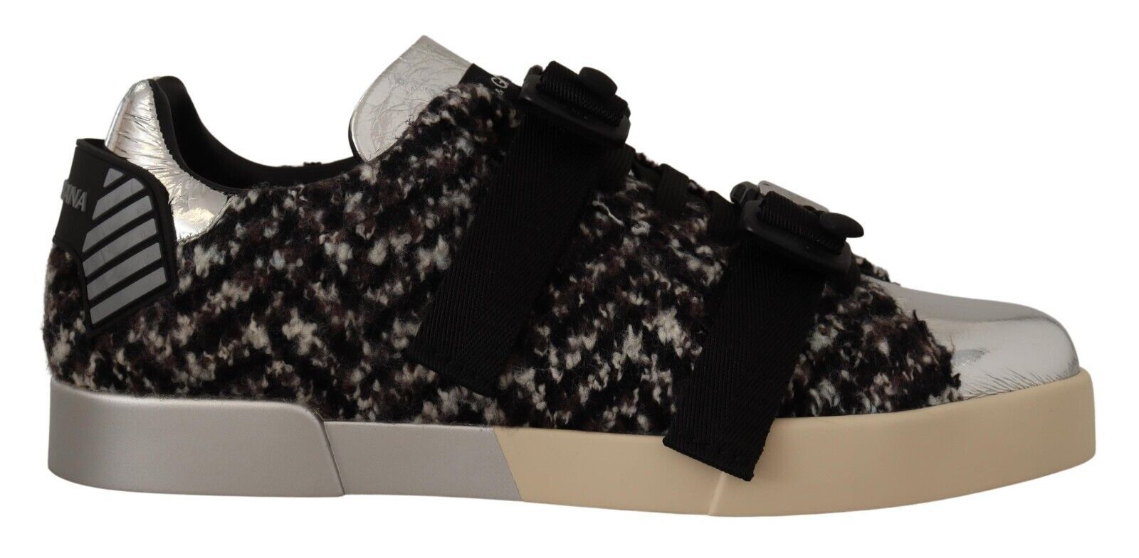 A single sneaker with a patterned upper and a white sole. The pattern consists of small, dark elements on a lighter backg