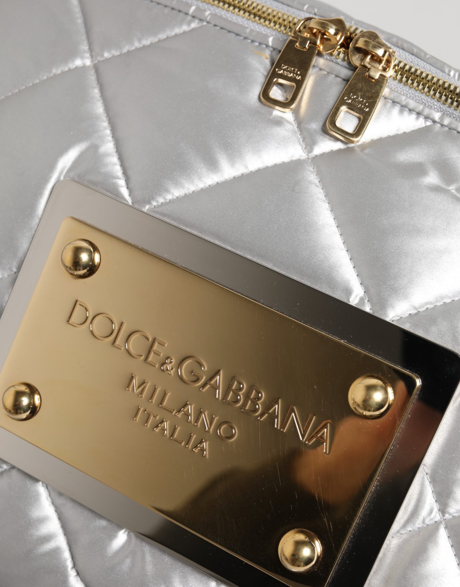 Gold branded metal plaque on a silver quilted purse