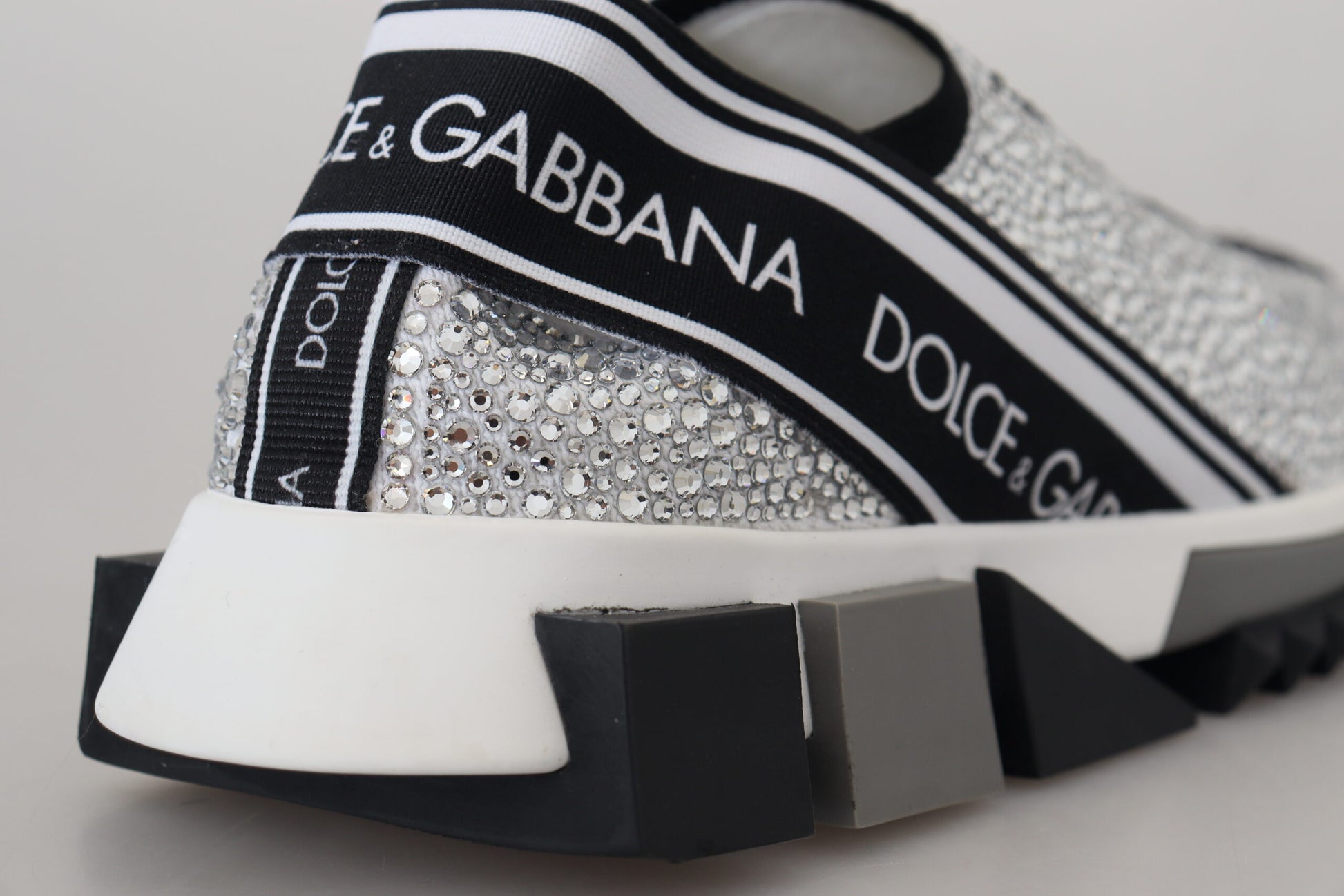 A pair of silver rhinestone-embellished sneakers with a black and white sole