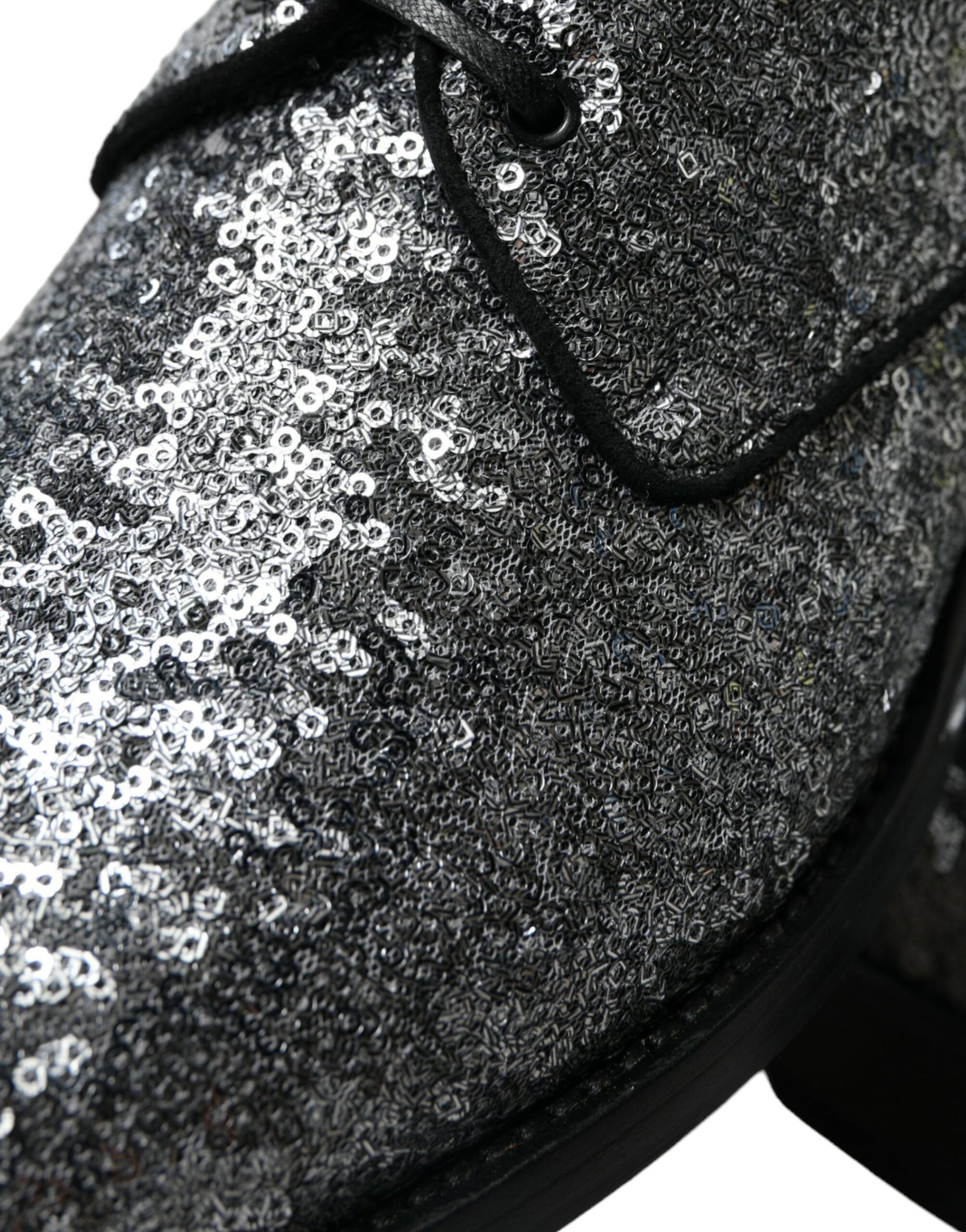 A single shoe with a glittery texture and a bow tie design on the toe cap. It appears to be a men's dress shoe due to its