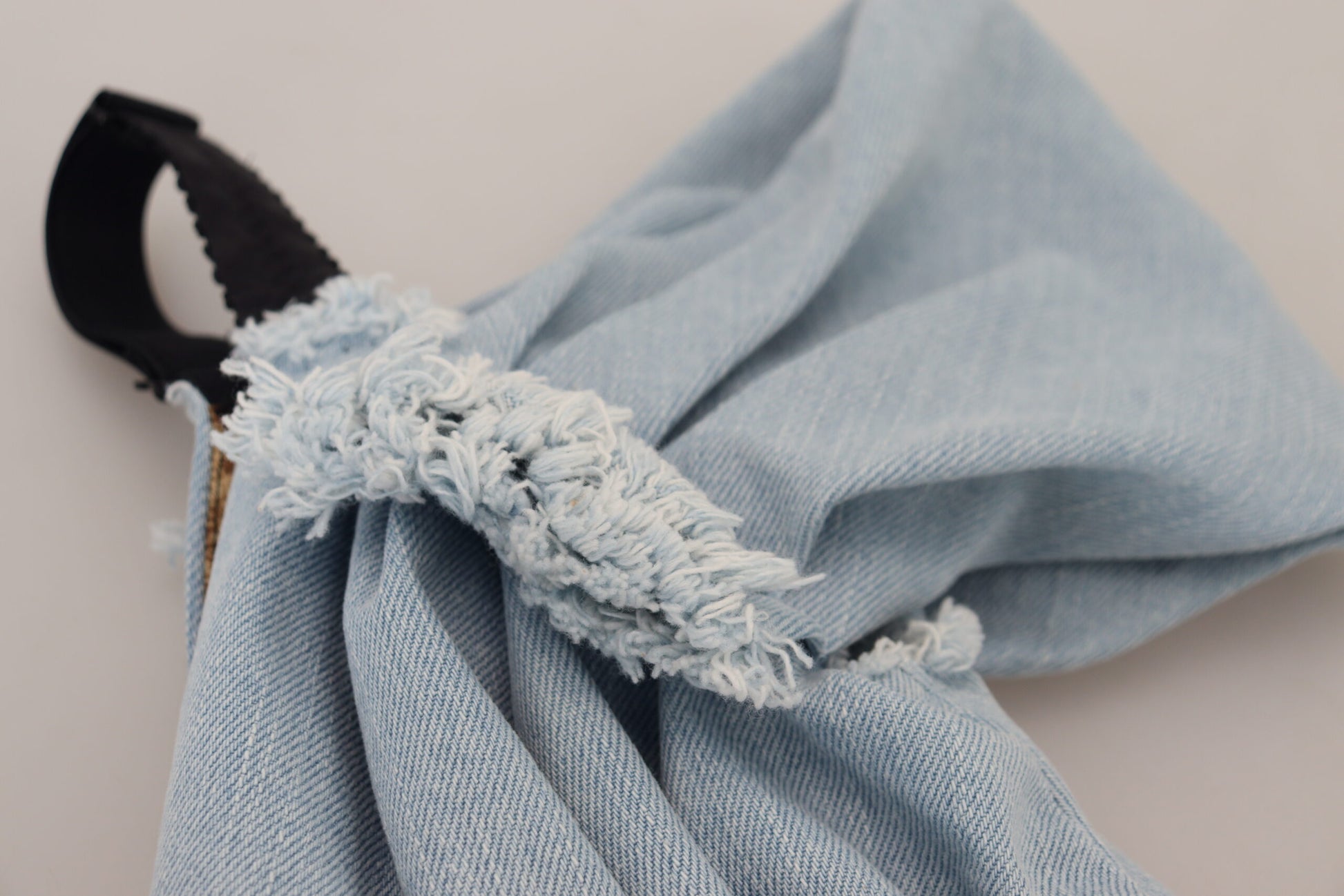 A blue denim dress with a patchwork design and fringe details on the sleeves