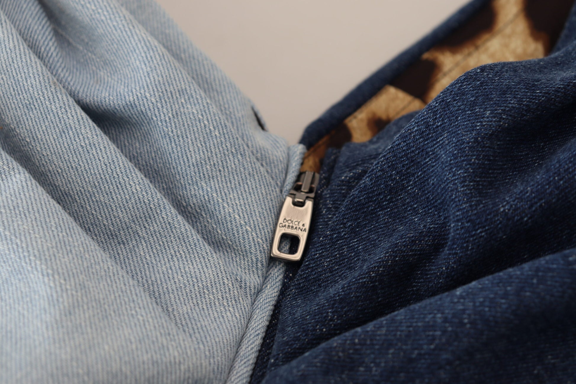 A blue denim dress with a patchwork design and silver zipper closure