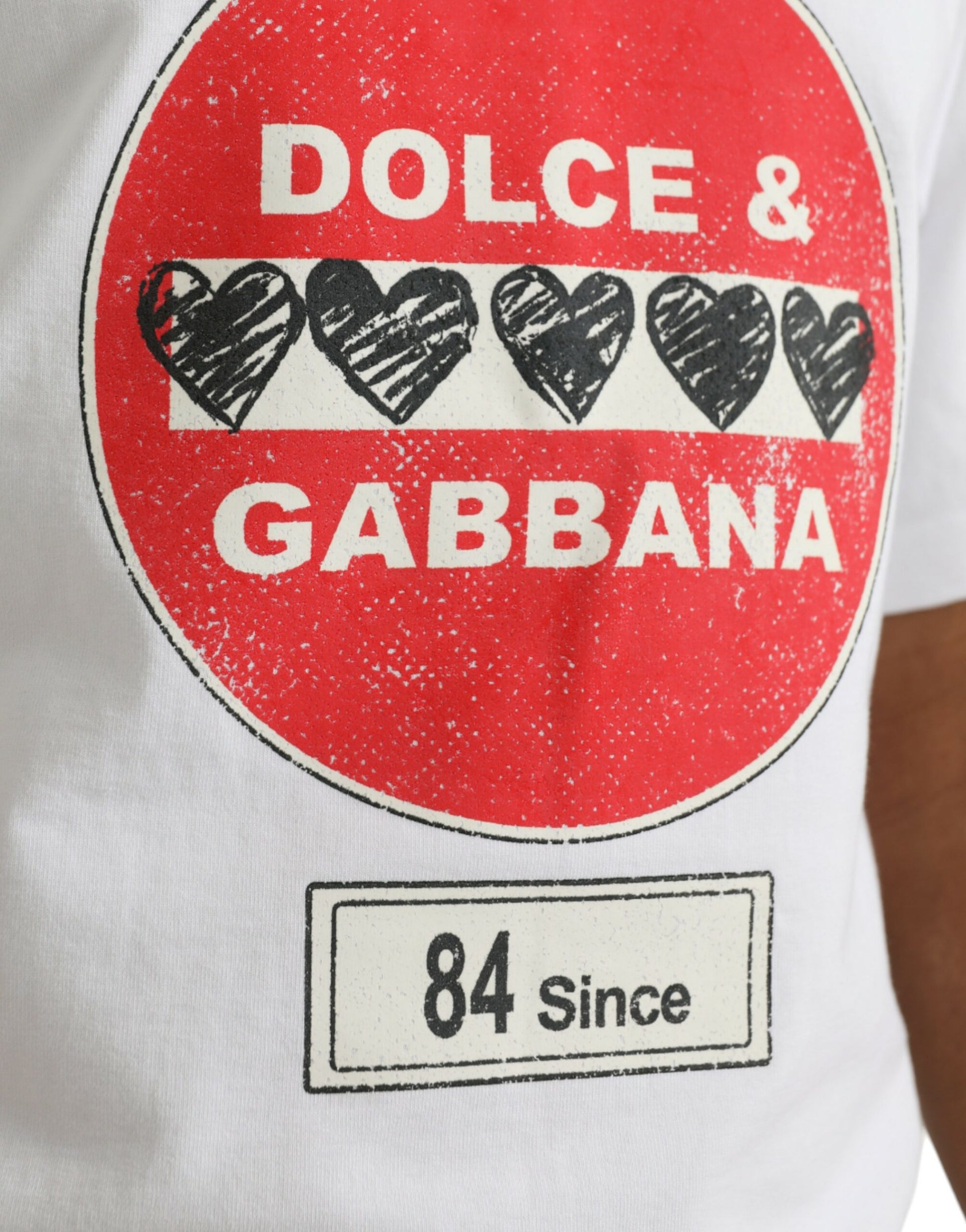 Red round sign on white shirt with black hearts and text