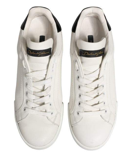 Pair of white leather sneakers with black accents and gold branding, featuring a low-top design