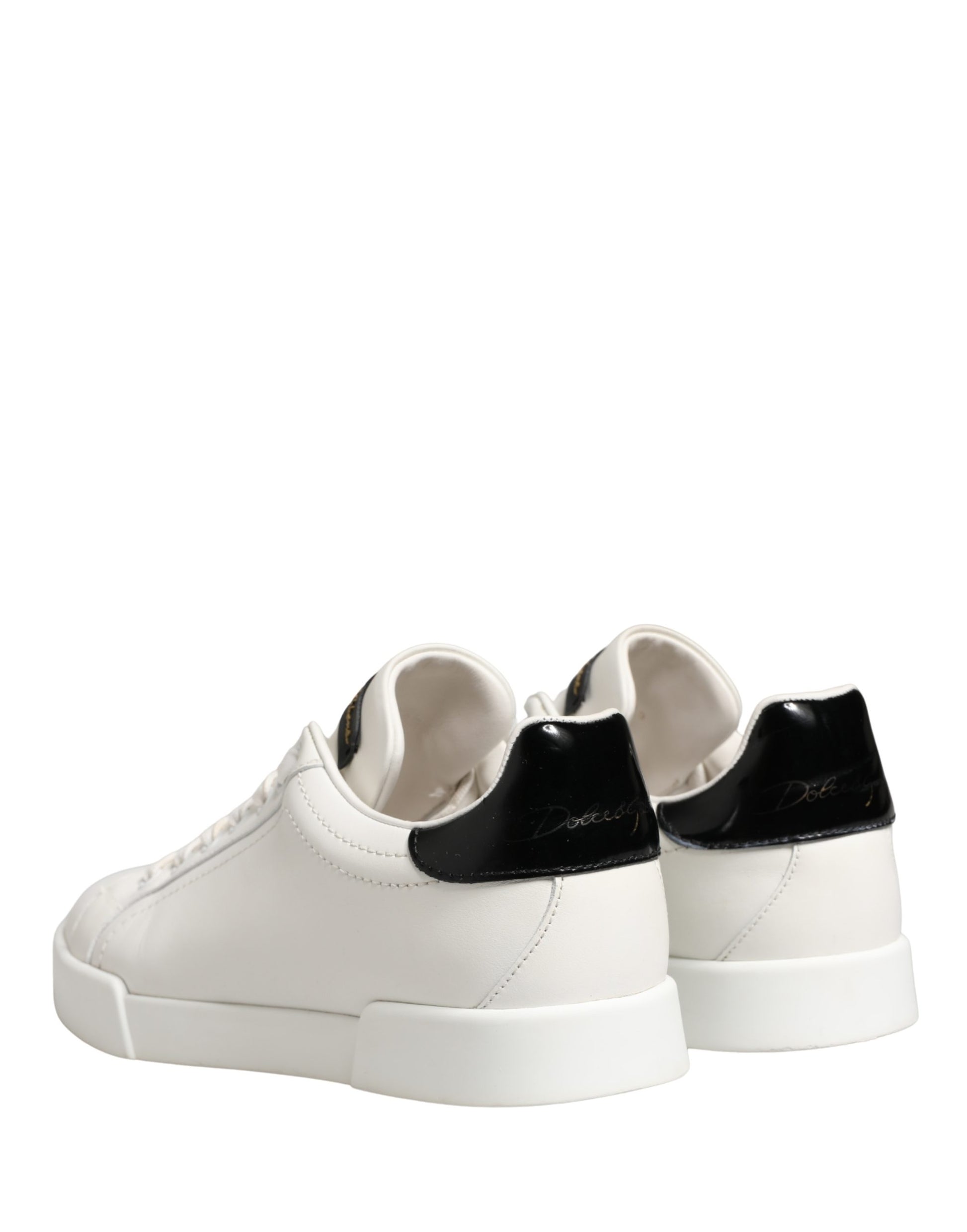 Pair of white and black leather sneakers with gold accents, featuring a low-top design