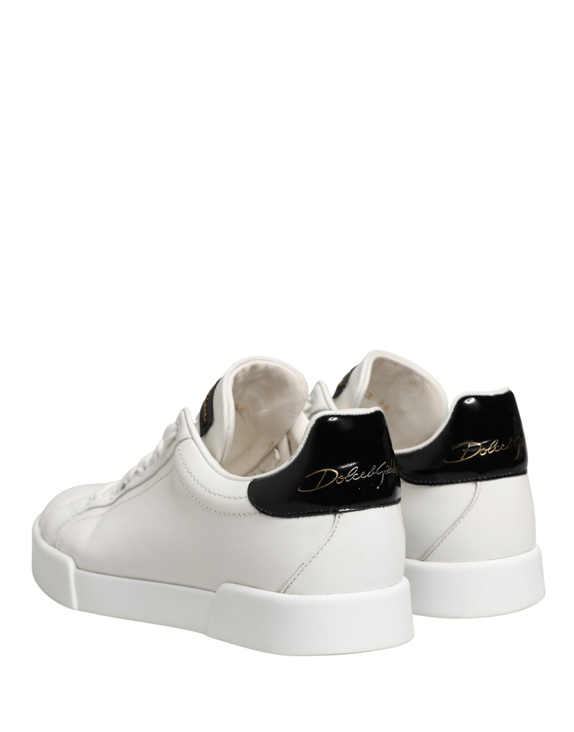Pair of white and black leather sneakers with gold accents, featuring a chunky sole design