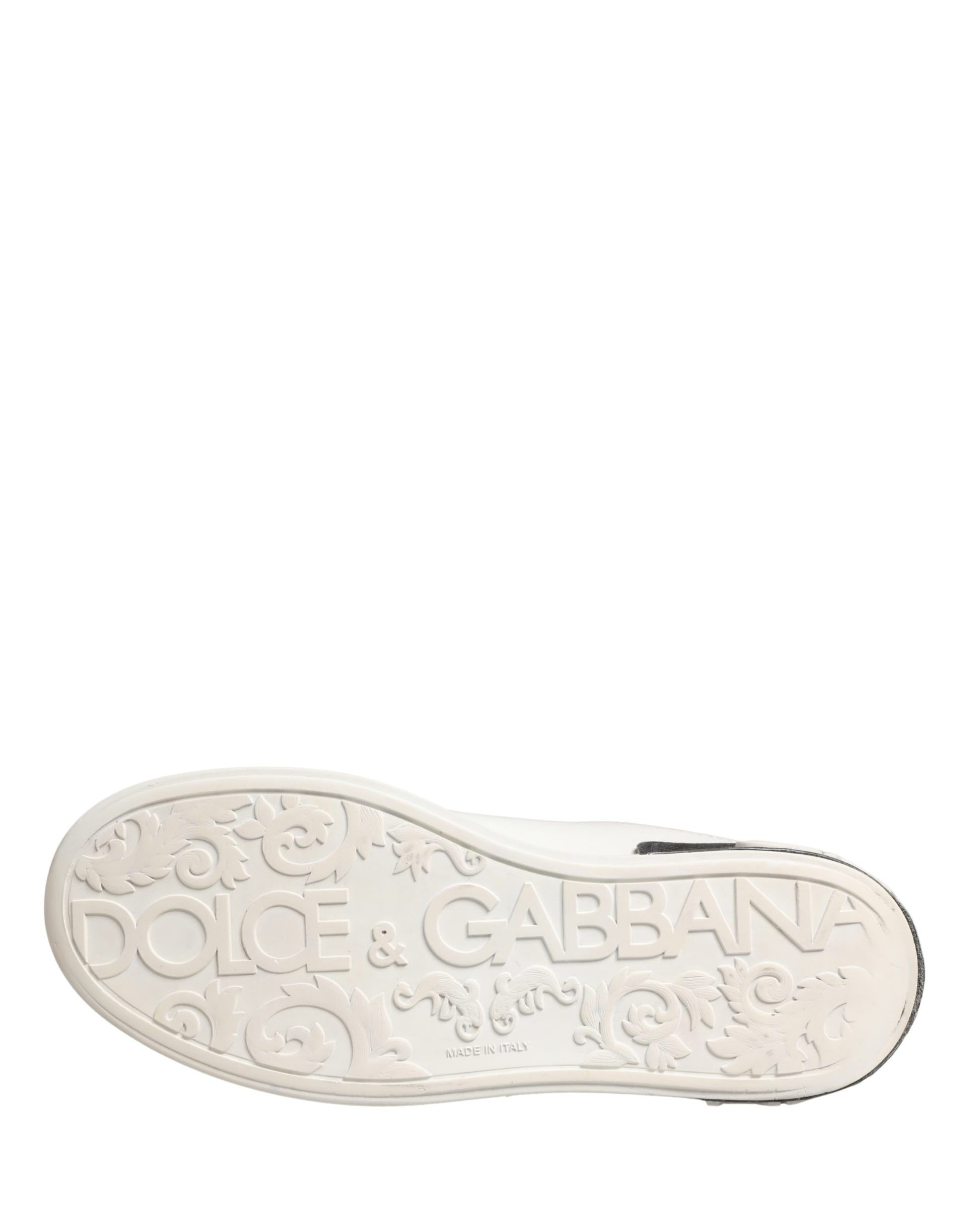 A single white shoe with black accents, featuring a detailed design on the side and the brand name "Dolce & Gabbana" printed