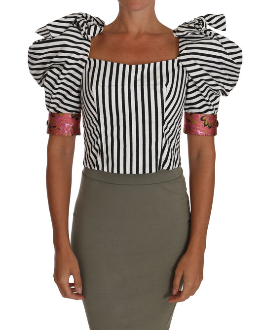 Woman wearing a black and white striped top with ruffled sleeves and a gray skirt