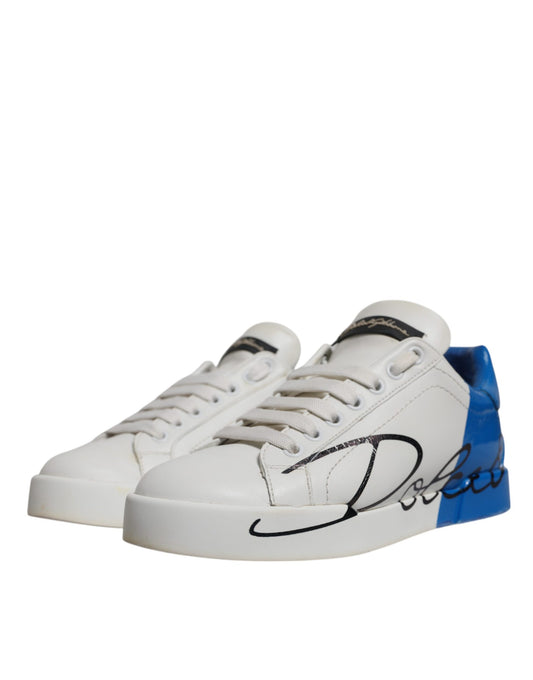 Pair of white sneakers with blue accents and a black signature on the side
