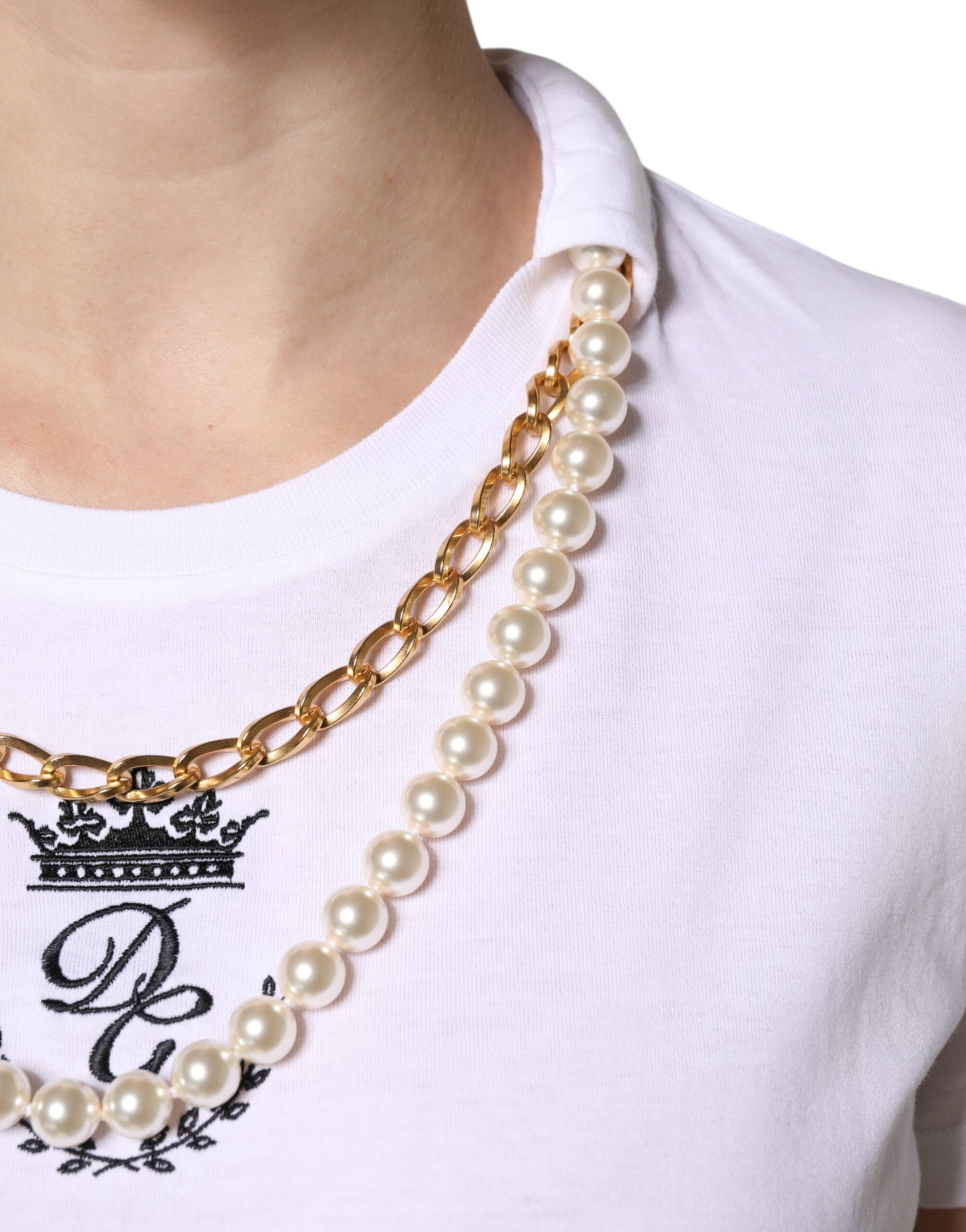 Woman wearing pearl necklace with crown design on shirt