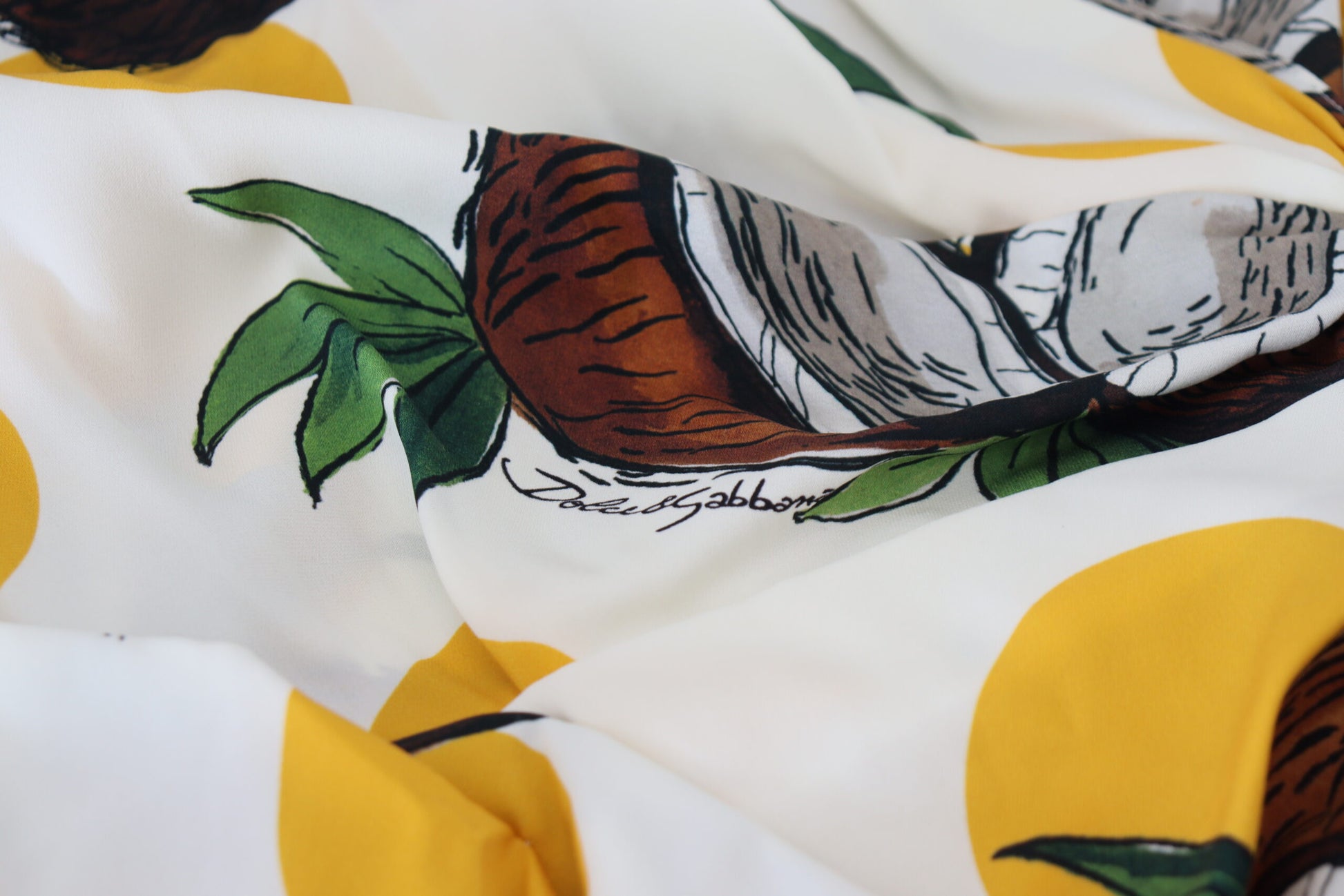 A white sheath dress with a coconut print and yellow accents, designed by Dolce & Gabbana