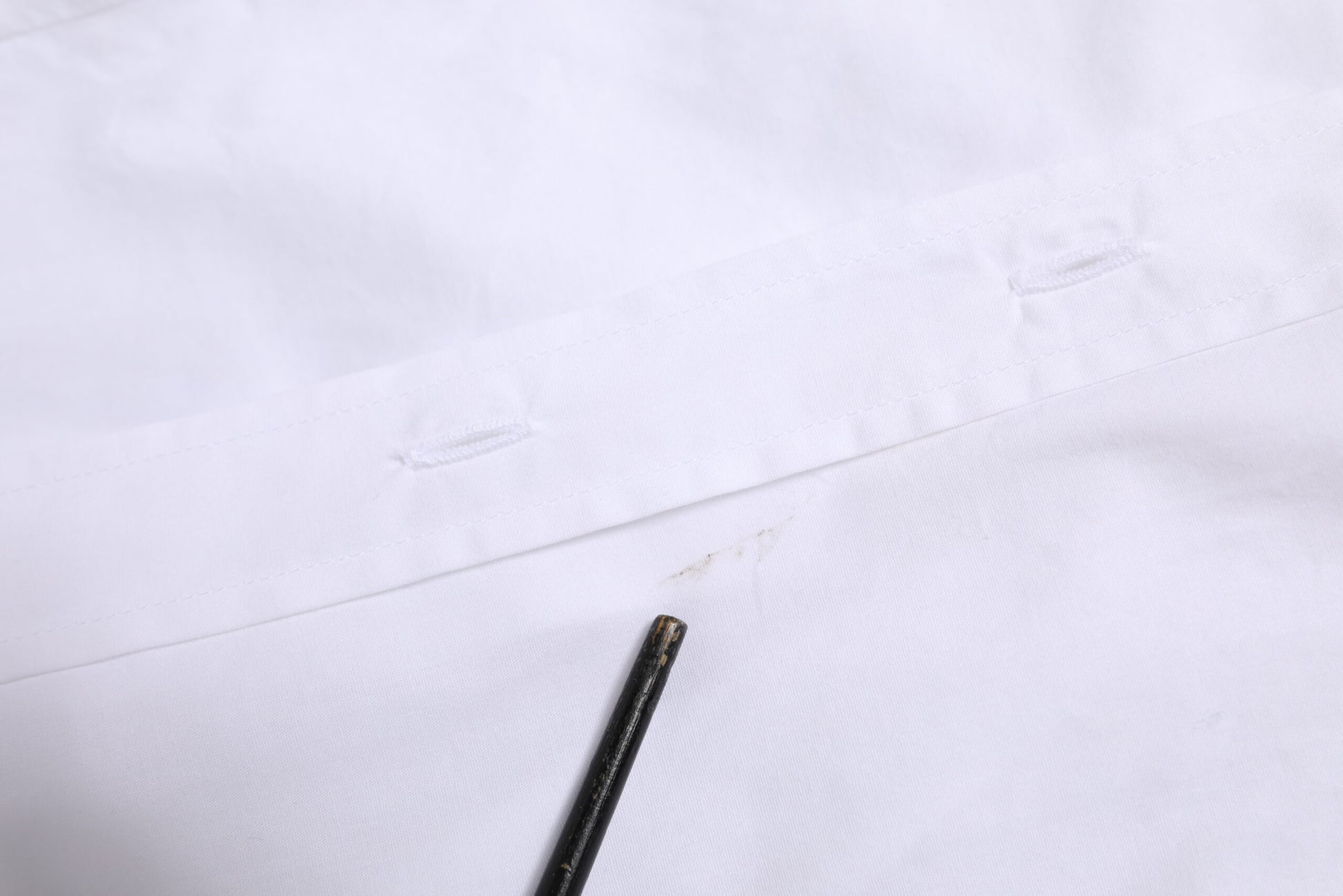 A white collared long sleeve dress shirt top with a black button closure